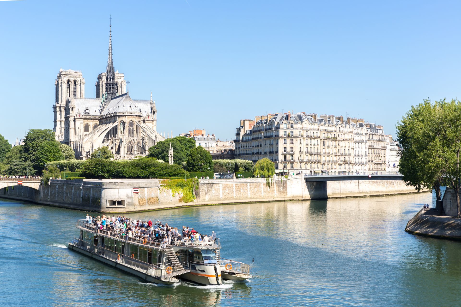 Notre Dame Cathedral overlooking a boat on the Seine River in Paris, France, on a sunny day.