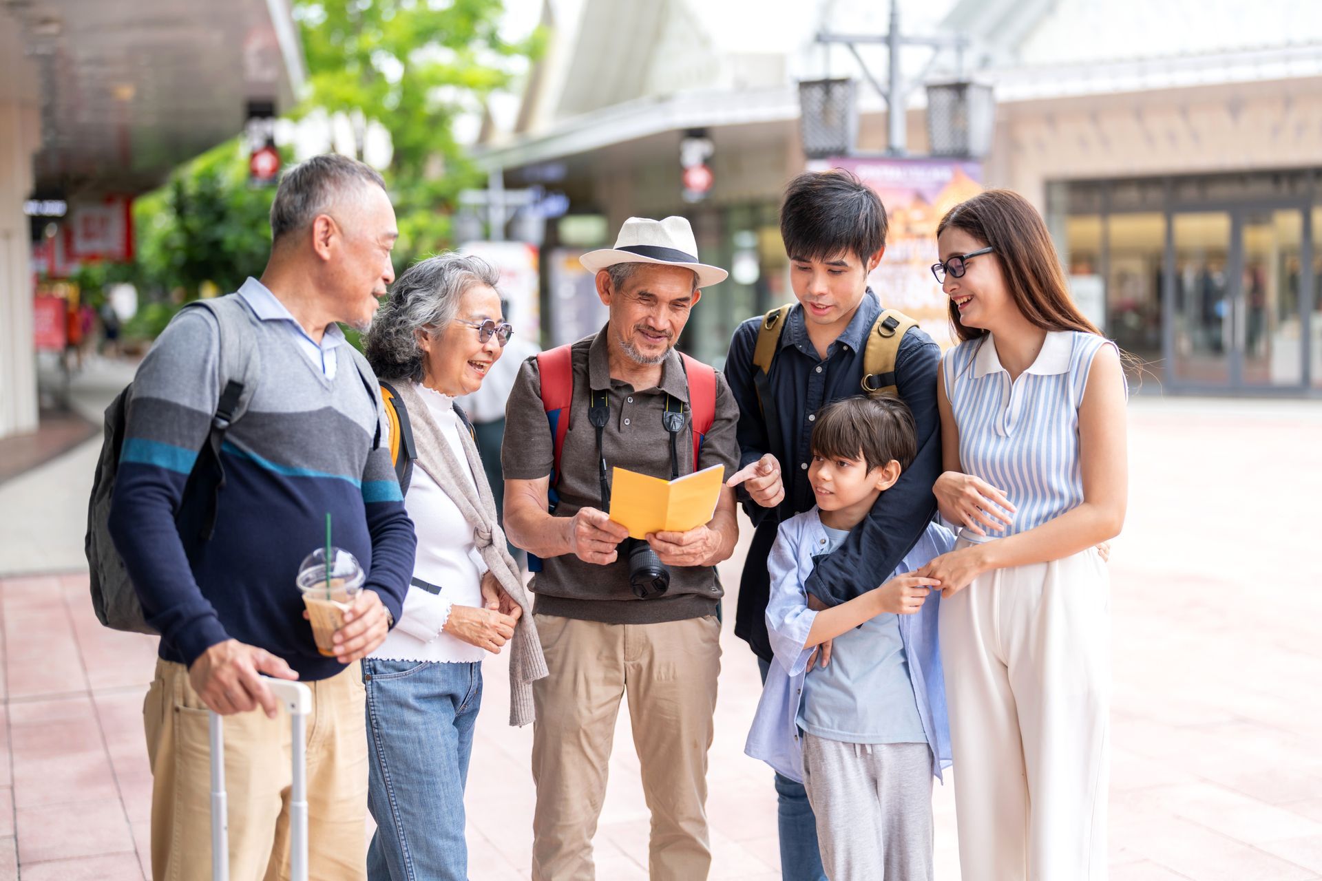 Family of six looking at a map outdoors, in a shopping area.