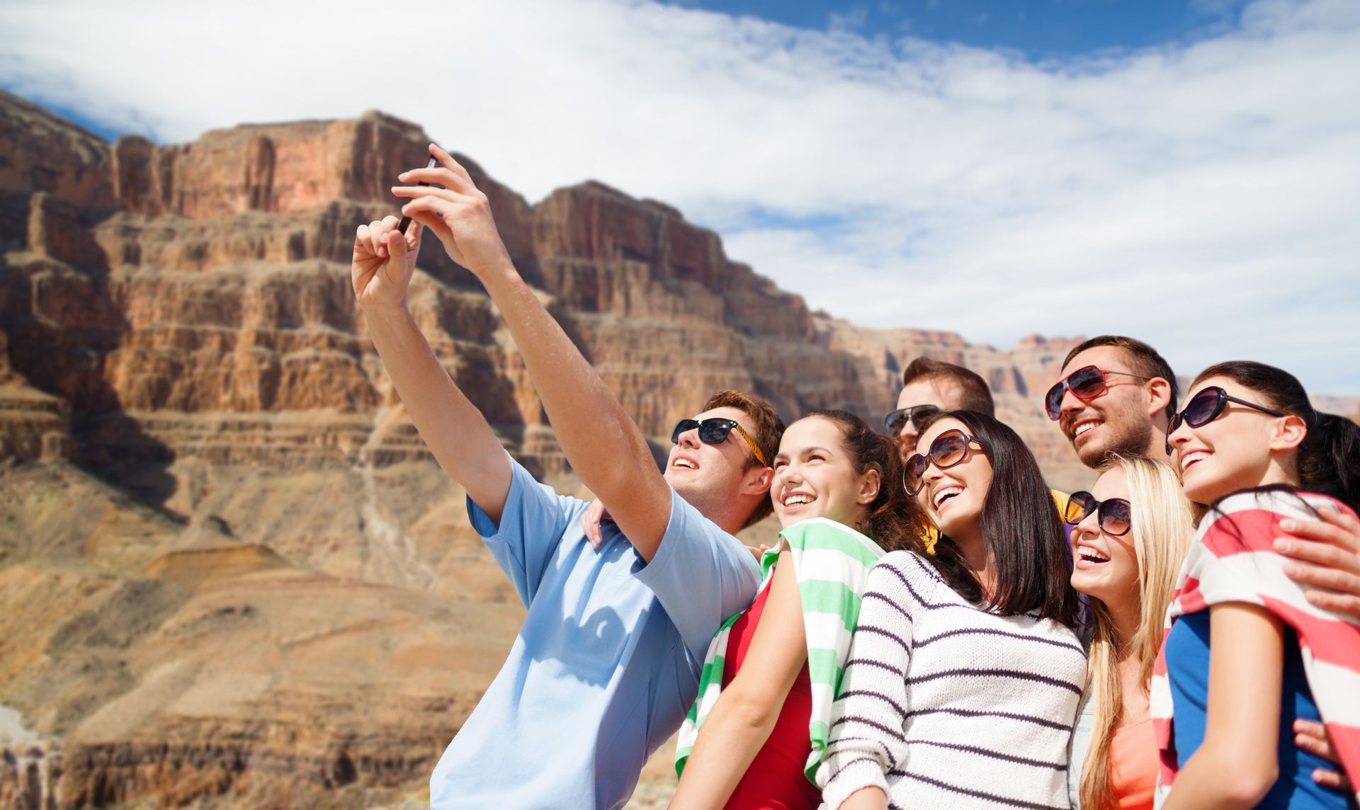 Group of people taking a selfie with a scenic canyon backdrop.