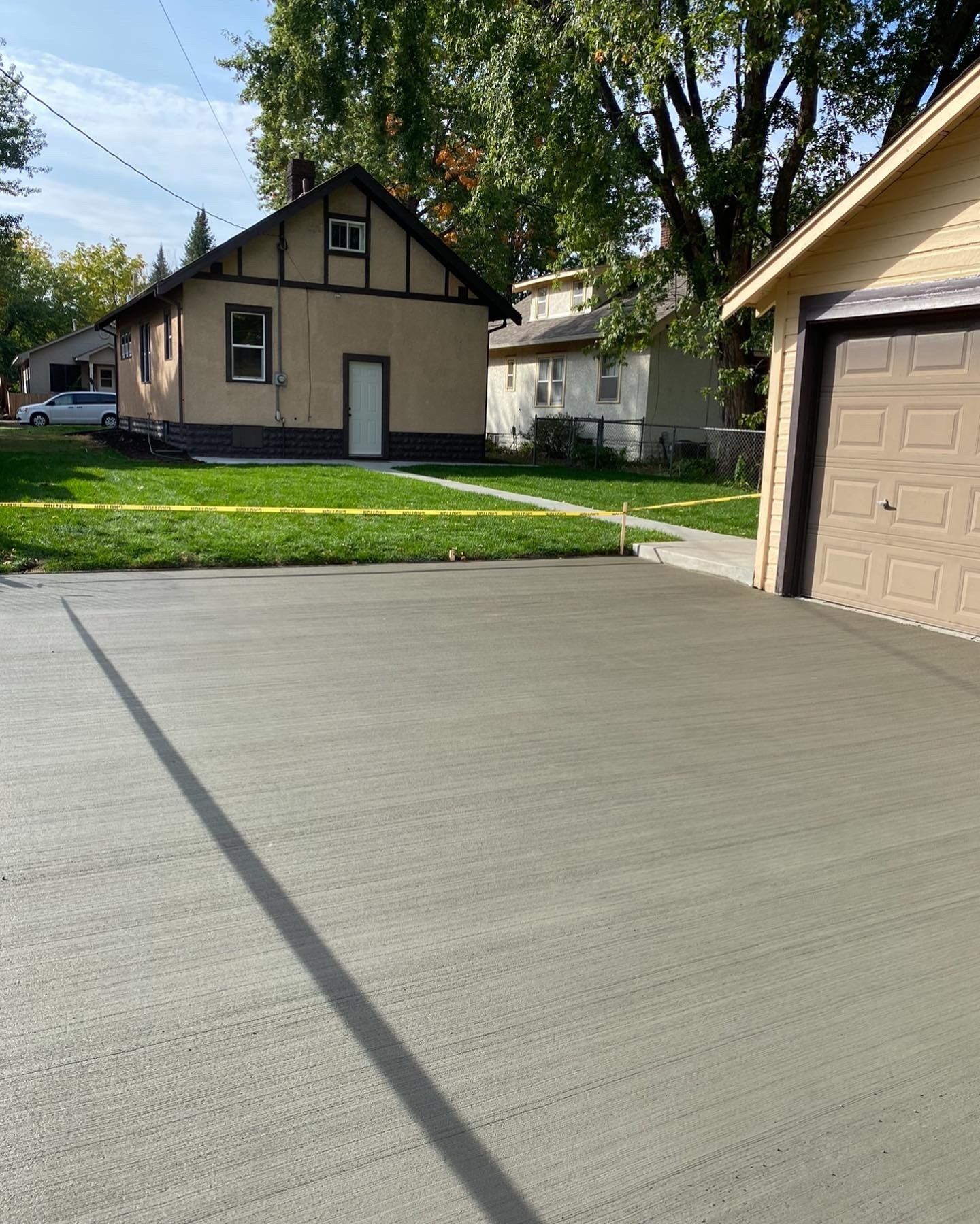 A concrete driveway in front of a house and garage