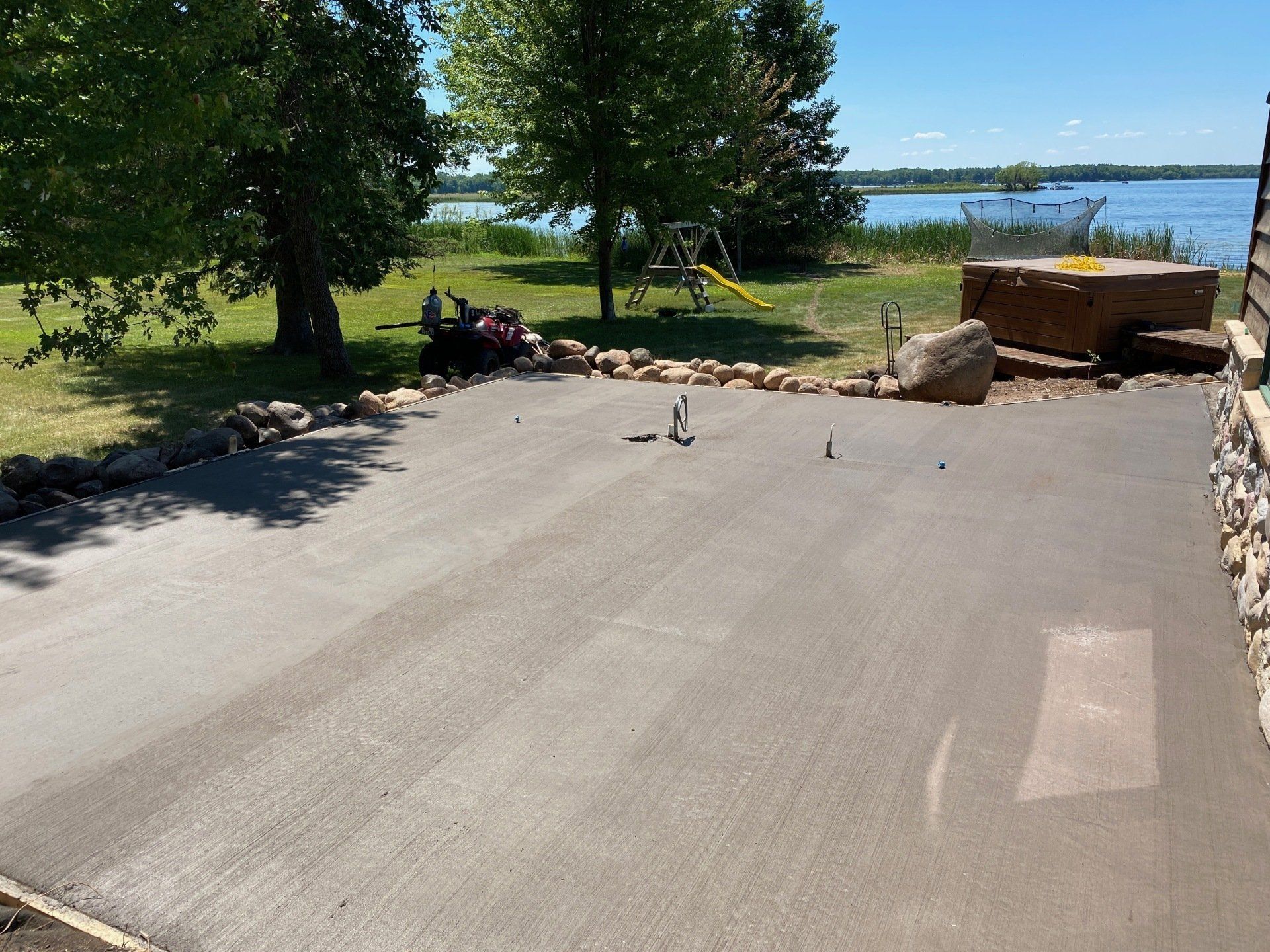 A driveway with a hot tub and a playground in the background