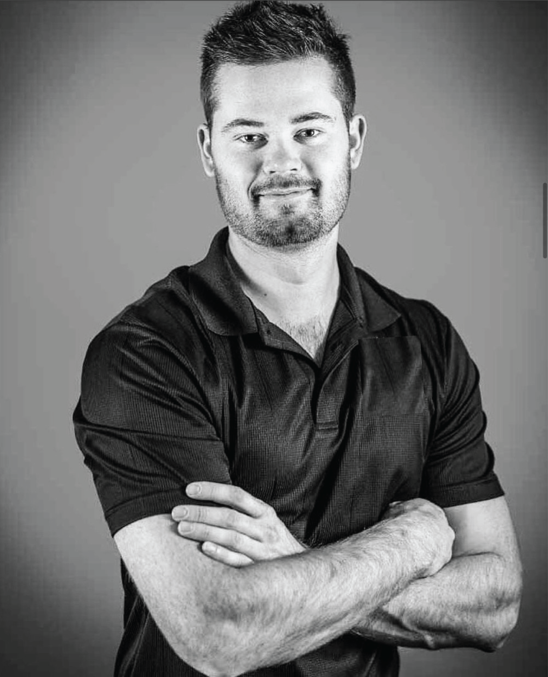 A black and white photo of a man with his arms crossed.