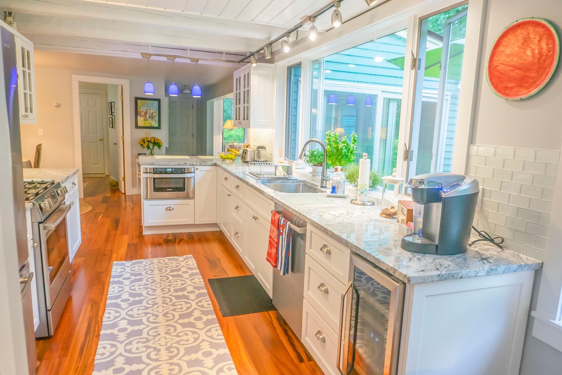 A kitchen with stainless steel appliances and a large island with stools.