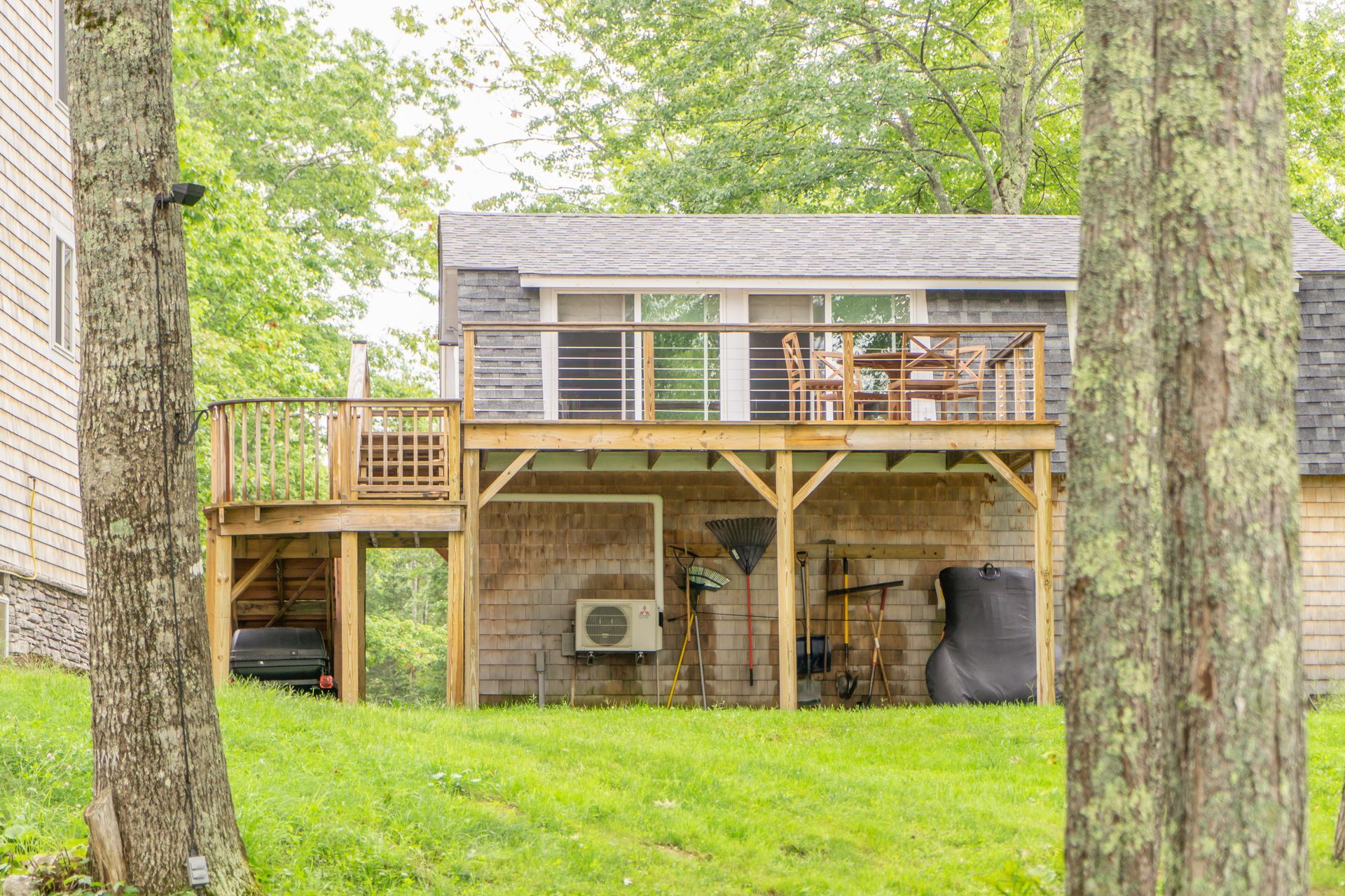 A house with a large deck is surrounded by trees and grass.