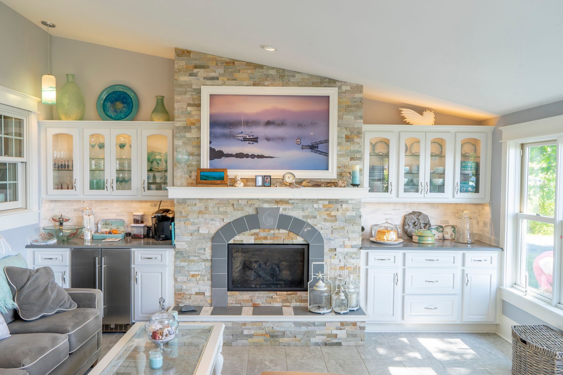 A living room with a stone fireplace , a couch , a coffee table and a picture on the wall.