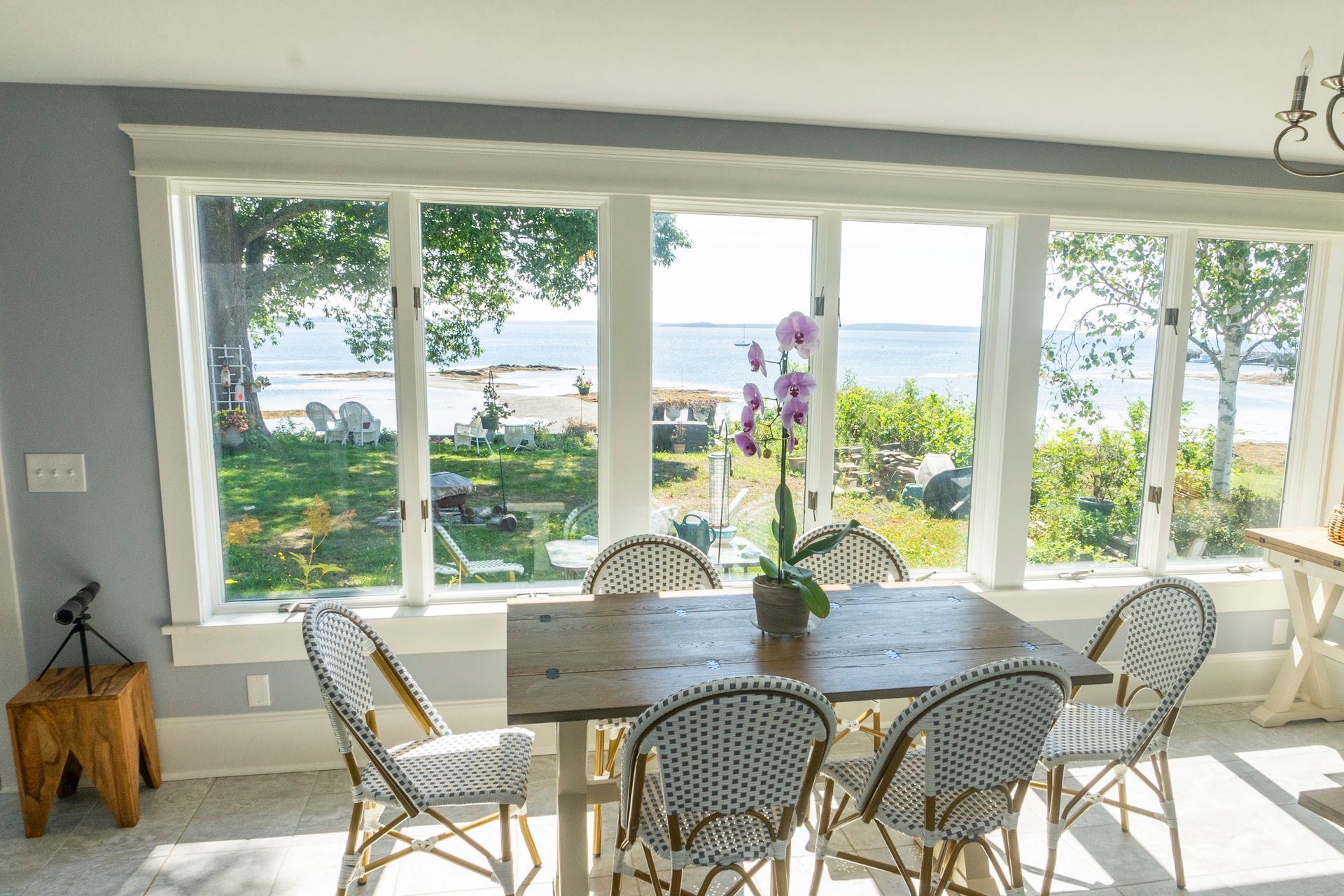 A dining room with a table and chairs and a view of the ocean.