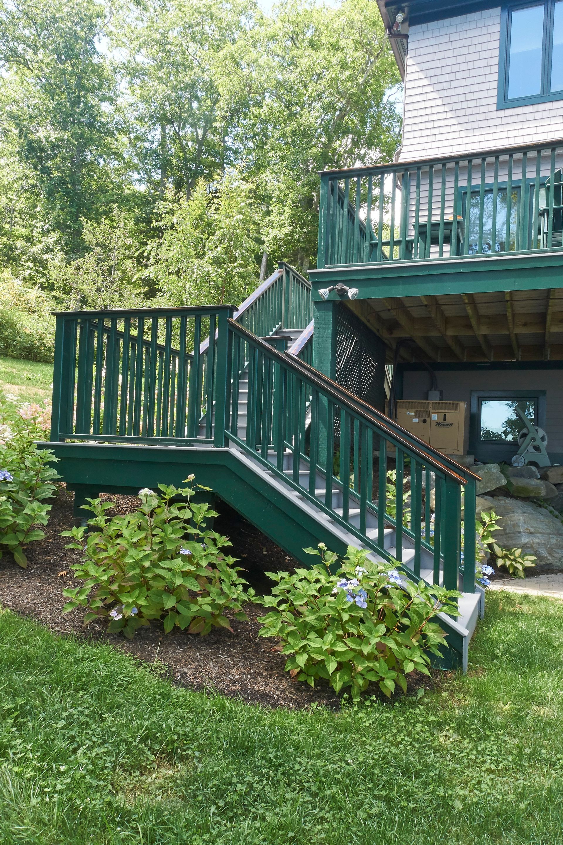 A house with a green deck and stairs leading up to it.