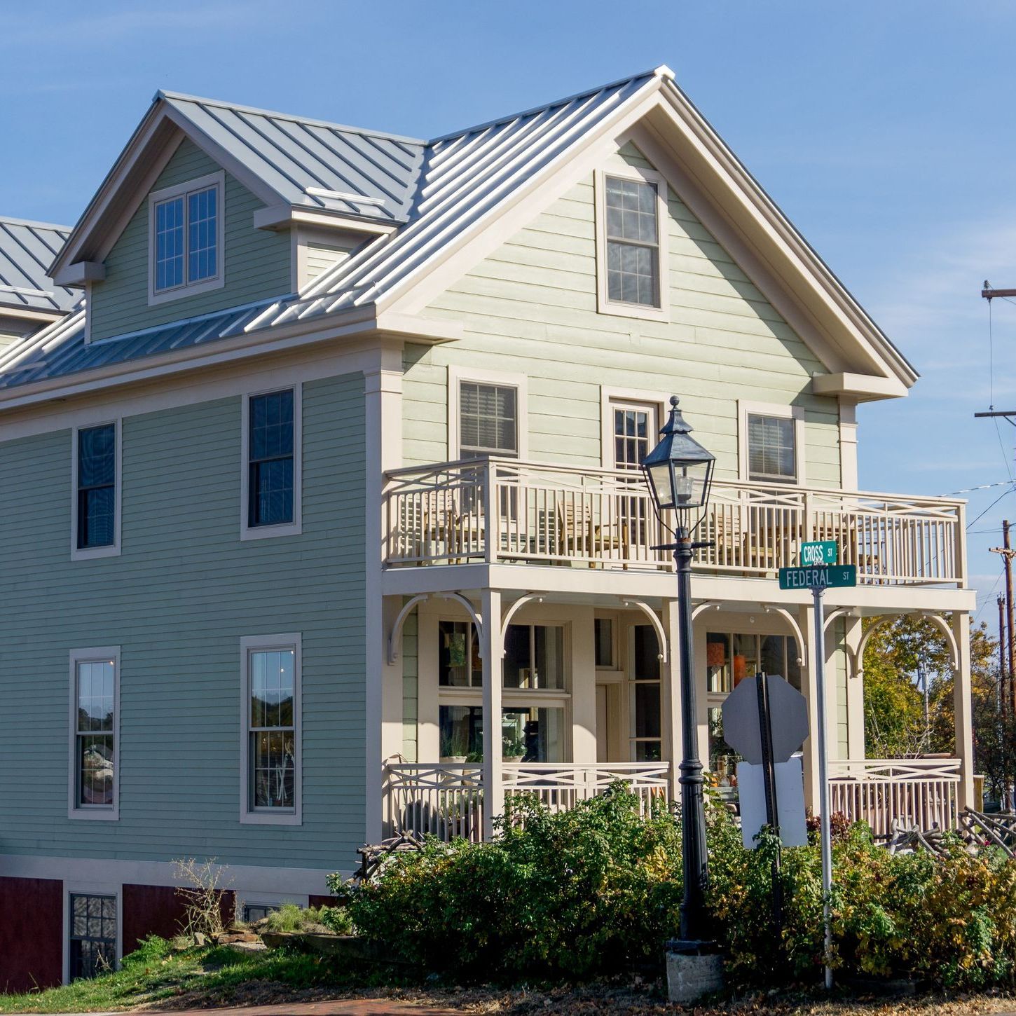 A white house with a black roof is surrounded by trees and bushes.