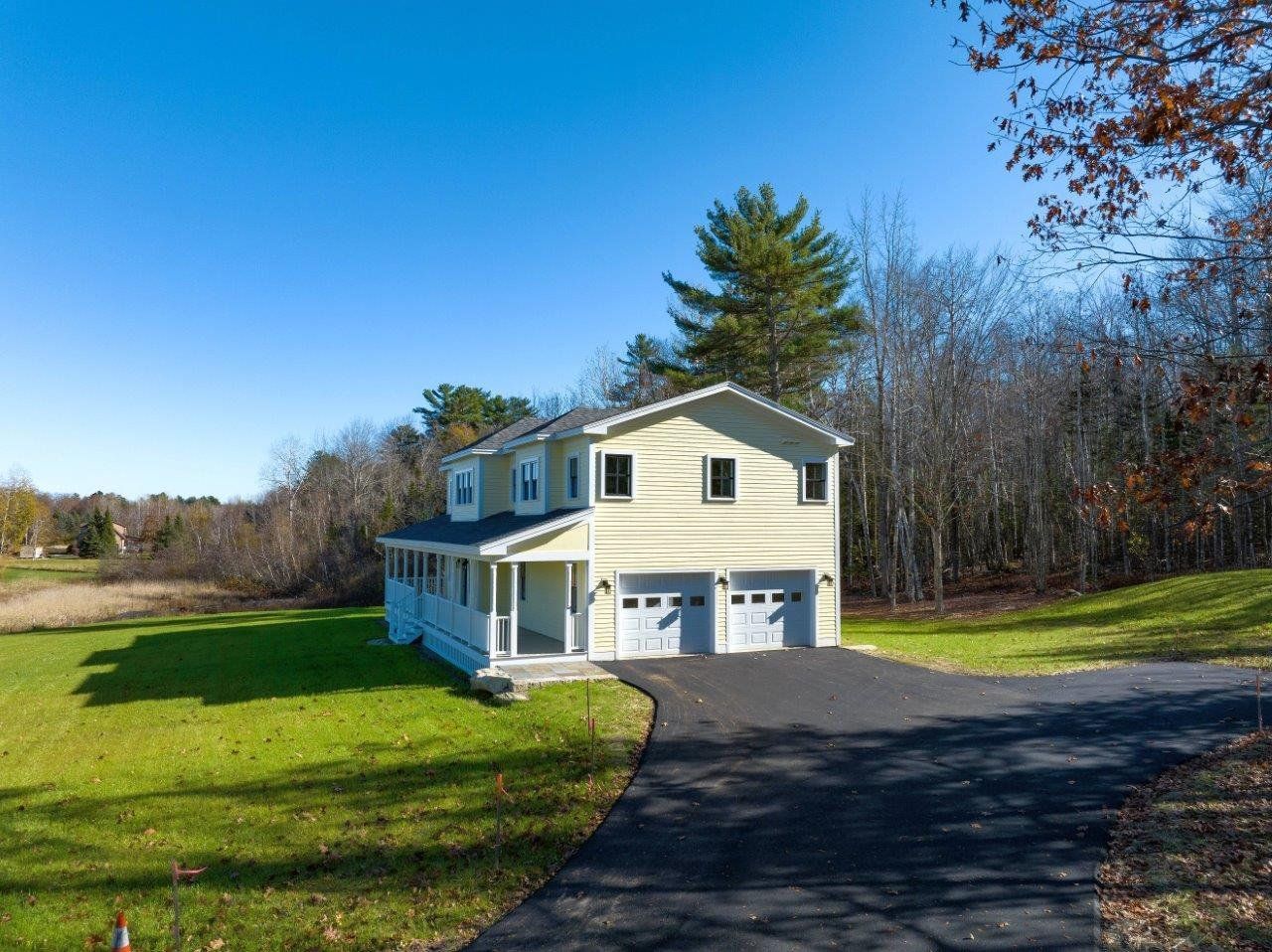 A house with two garages is sitting on top of a lush green field.