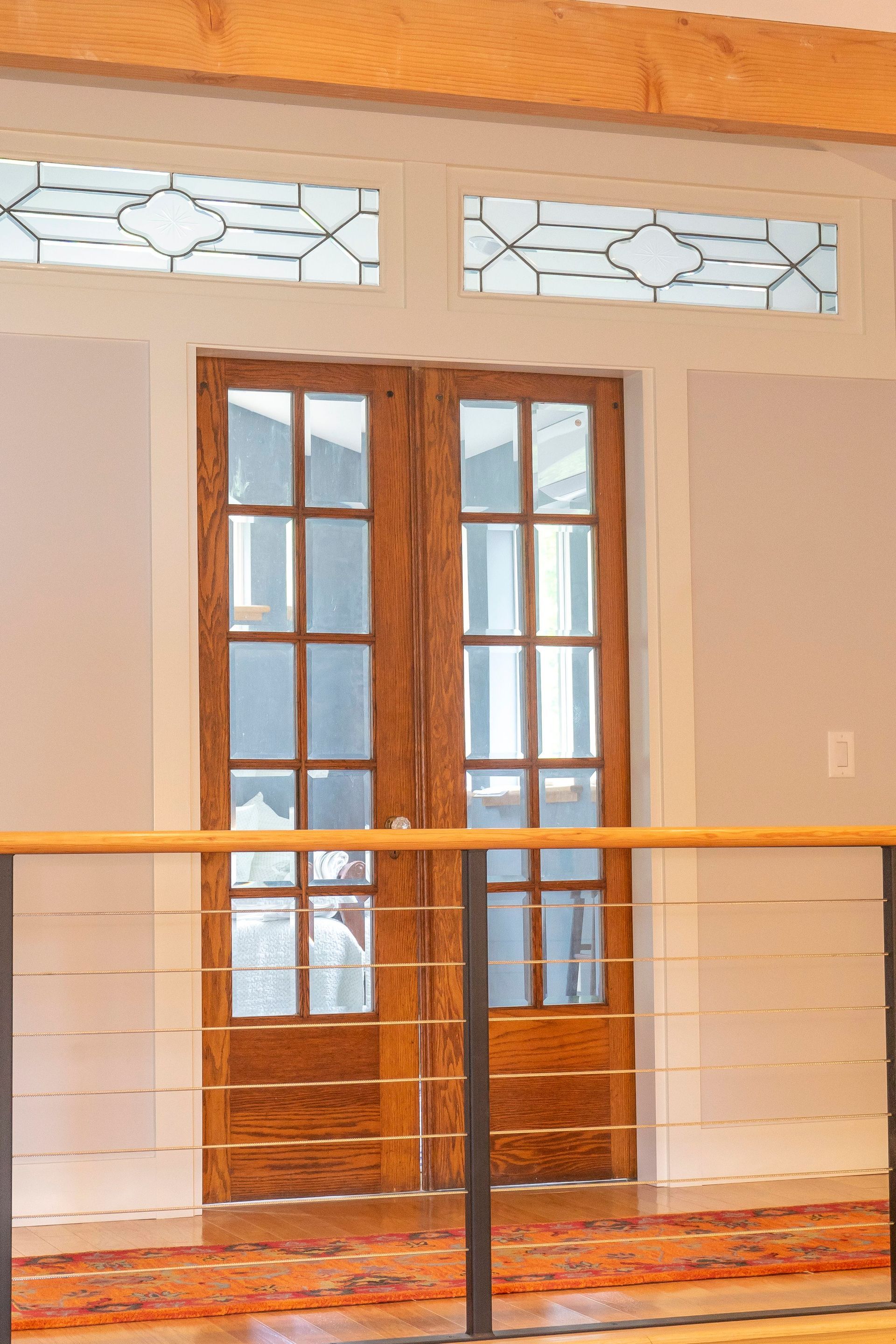 A pair of wooden doors with stained glass windows and a metal railing.