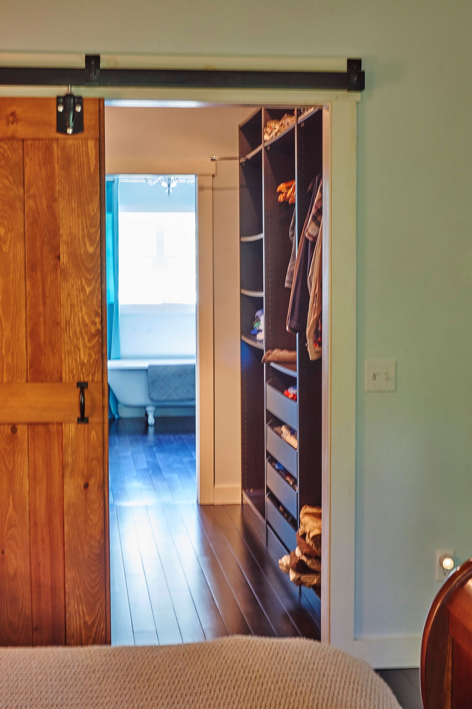 A bedroom with a sliding barn door leading to a walk in closet