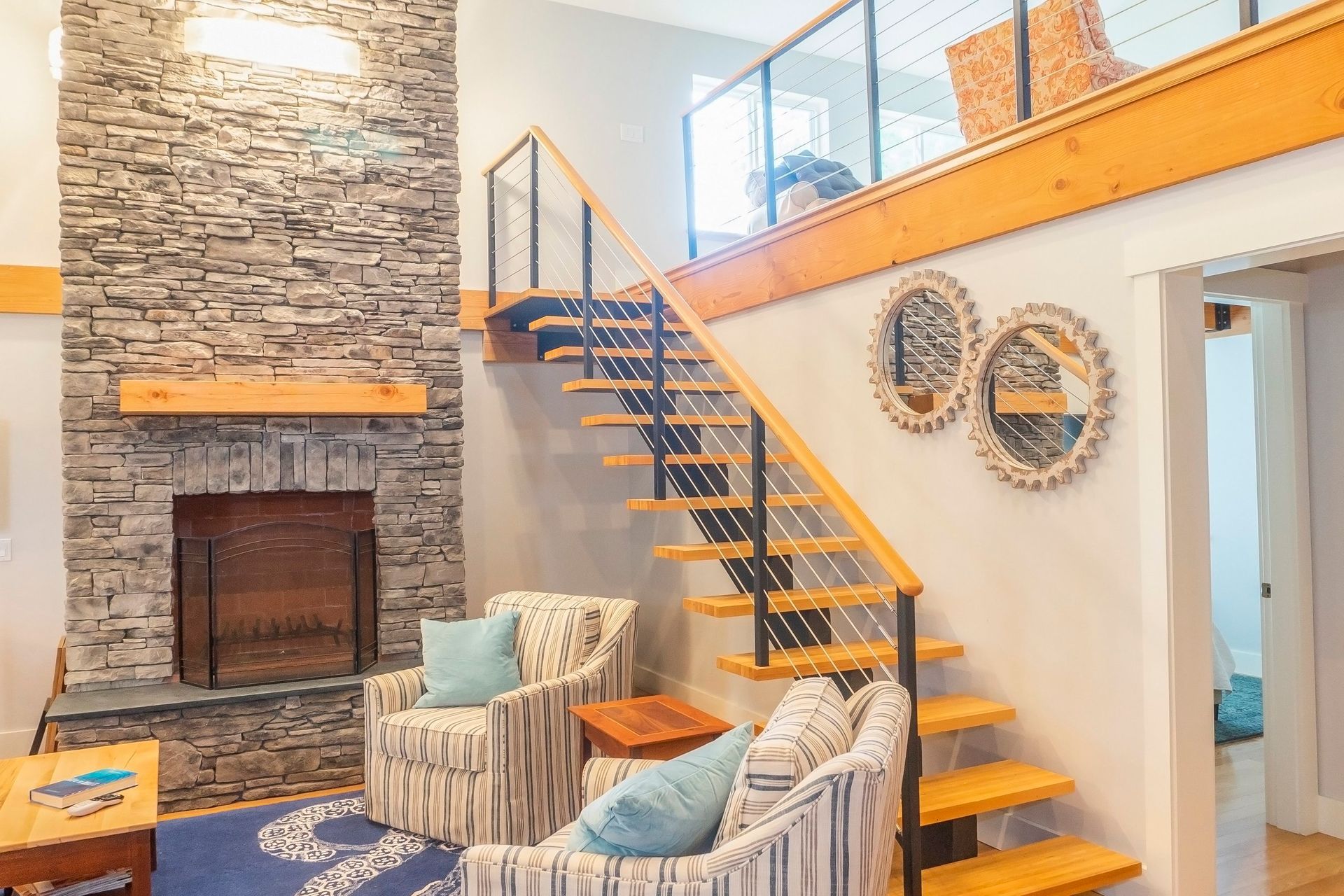 A living room with a fireplace and stairs leading up to the second floor.