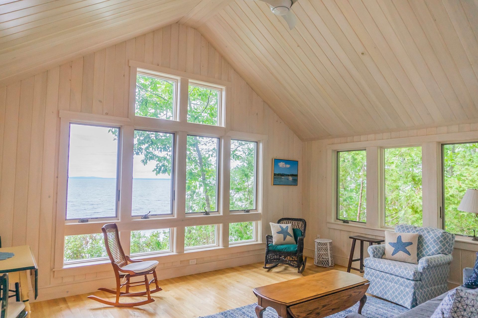 A living room with a lot of windows and a view of the ocean.
