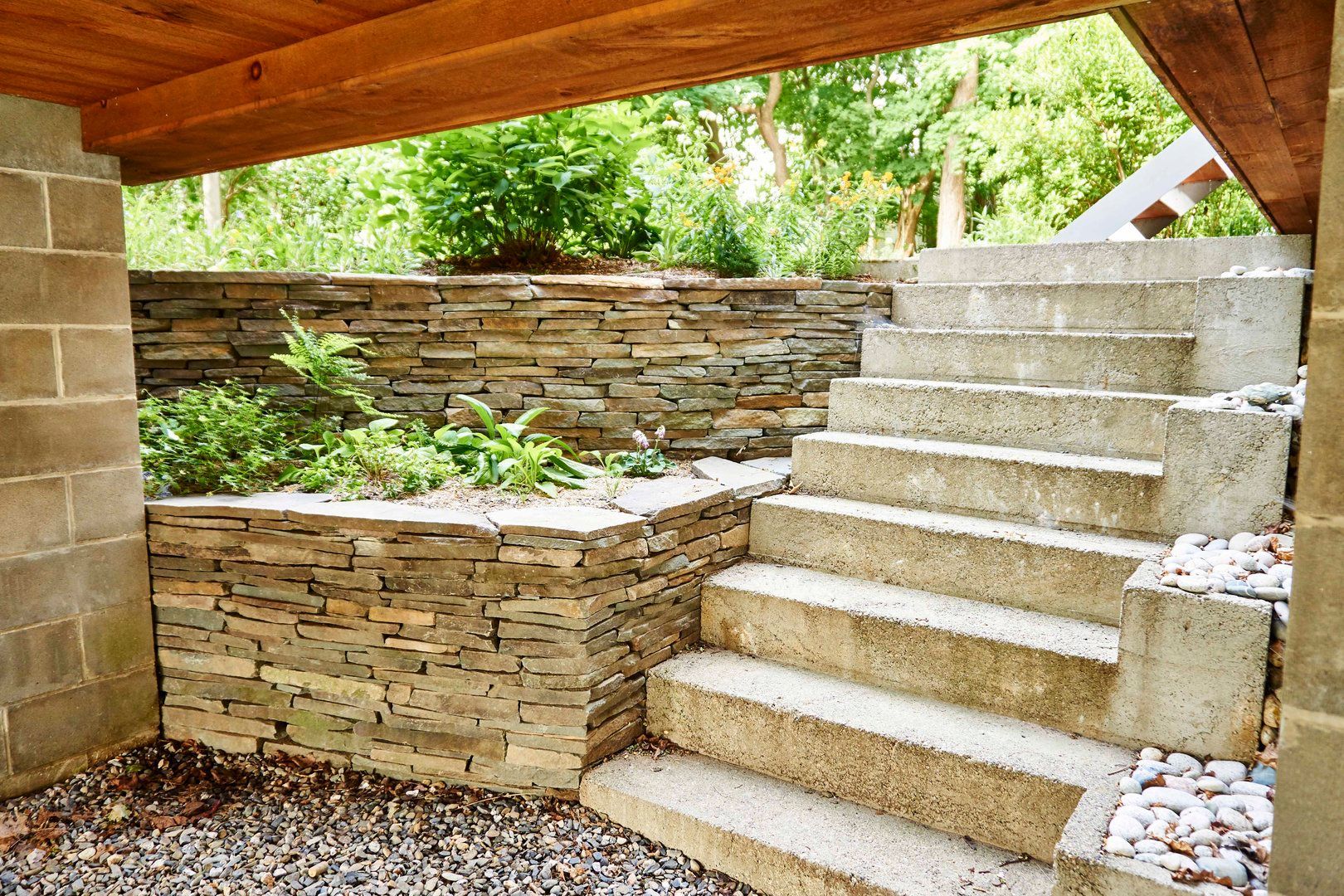 Whitecap Builders installed stone steps and a retaining wall for a sloped yard in Swanville, Maine.