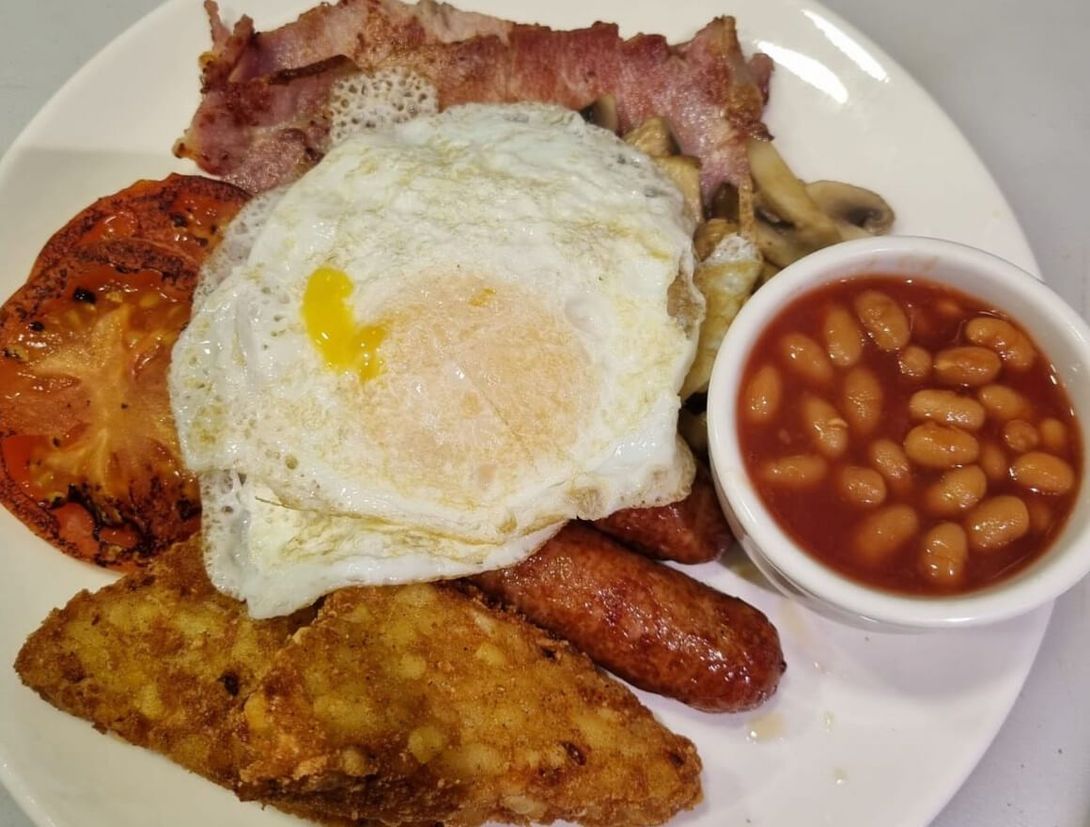a white plate topped with eggs bacon sausage tomatoes and baked beans