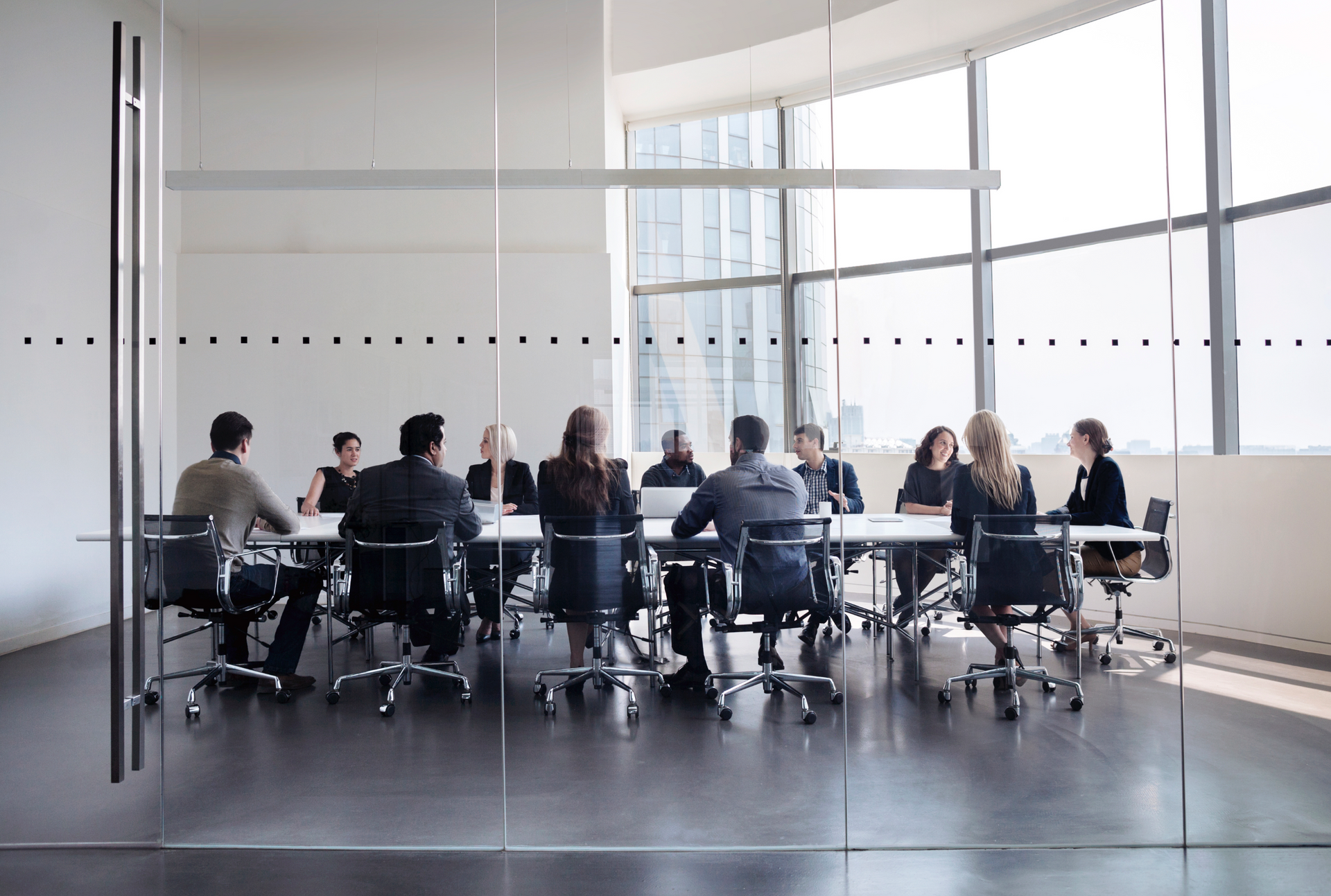 A group of people are sitting at a long table in a conference room.