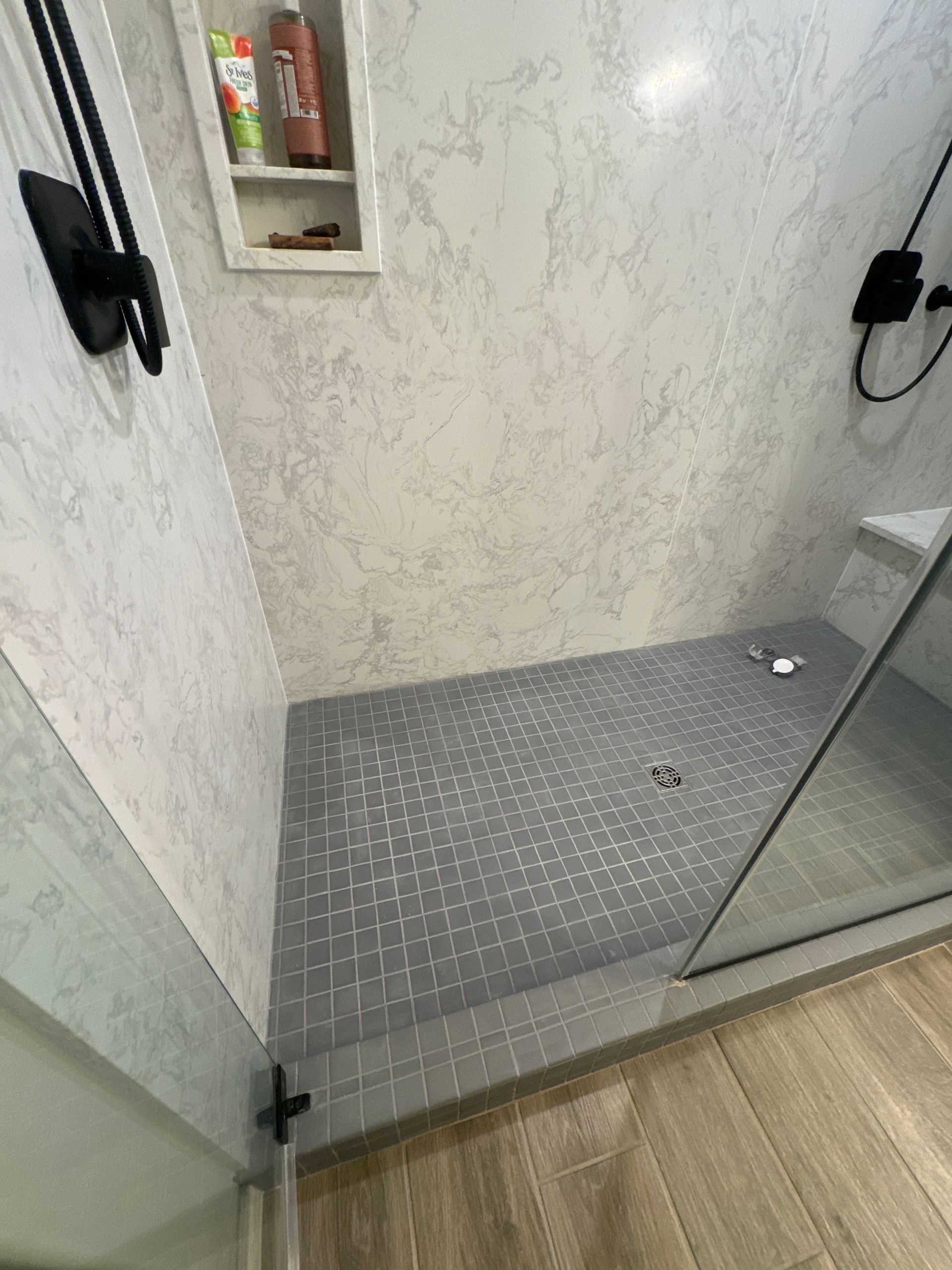 A bathroom with a walk in shower and a glass door.