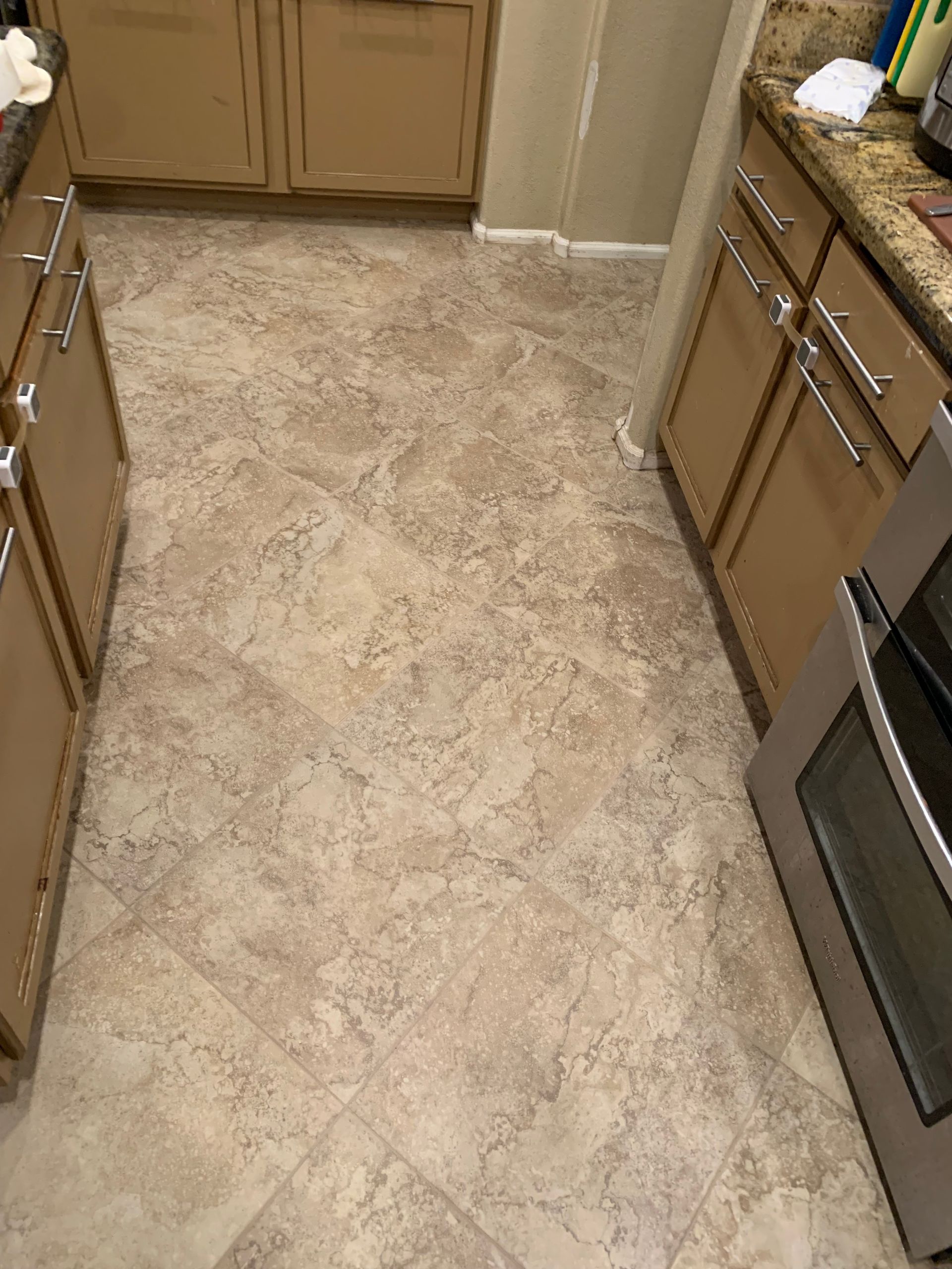 A kitchen with a tile floor , stainless steel appliances , and wooden cabinets.