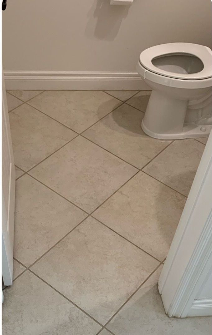 A toilet is sitting on a tiled floor in a bathroom.