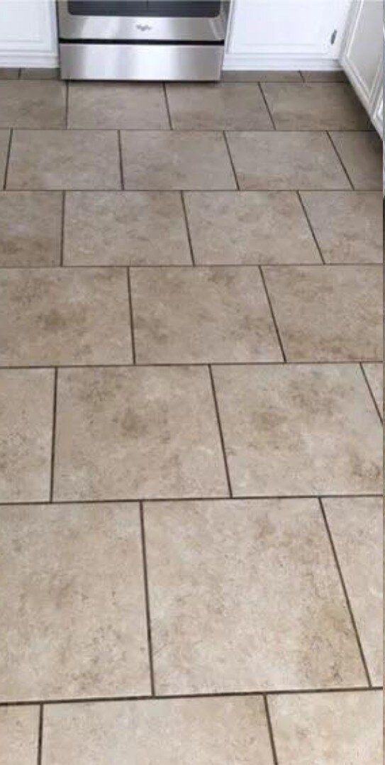 A kitchen floor with tiles and a stove in the background.