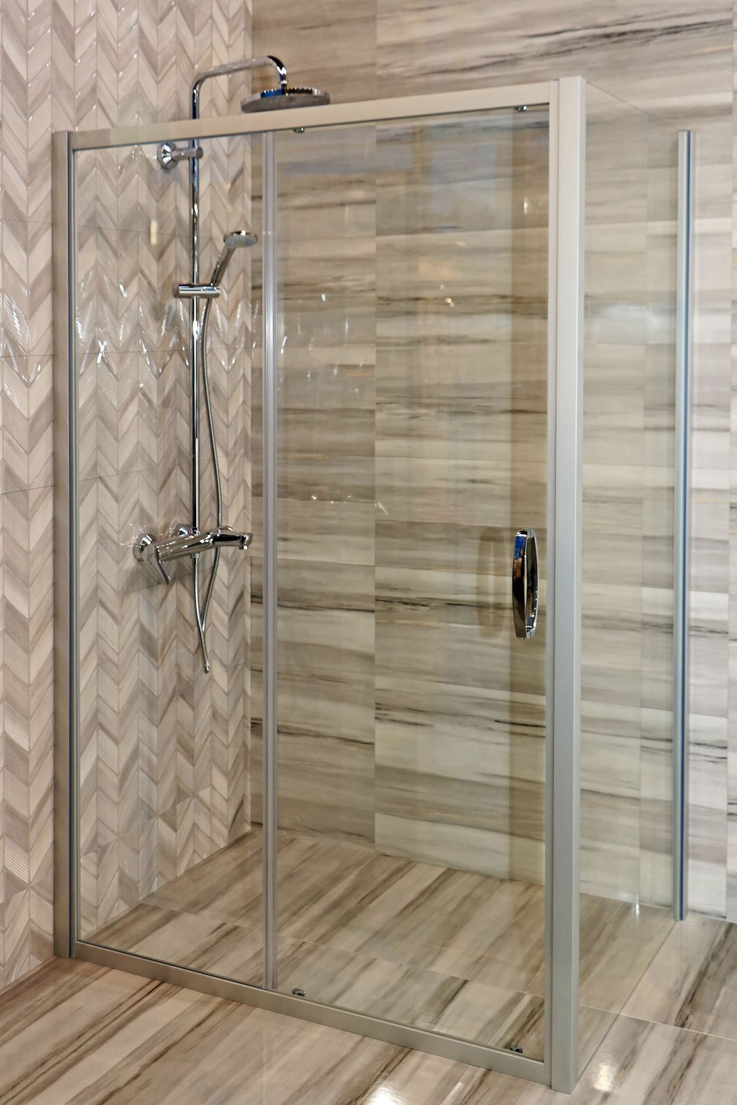 A shower stall with sliding glass doors and a shower head in a bathroom.