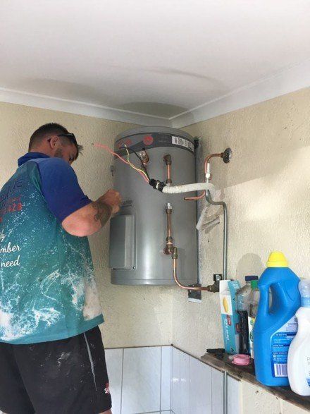 Plumber installing hot water system indoors - Darwin, NT