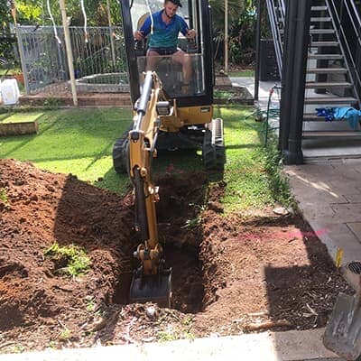 excavator digging up plumbing pipework to discover blockage in drains -Darwin NT