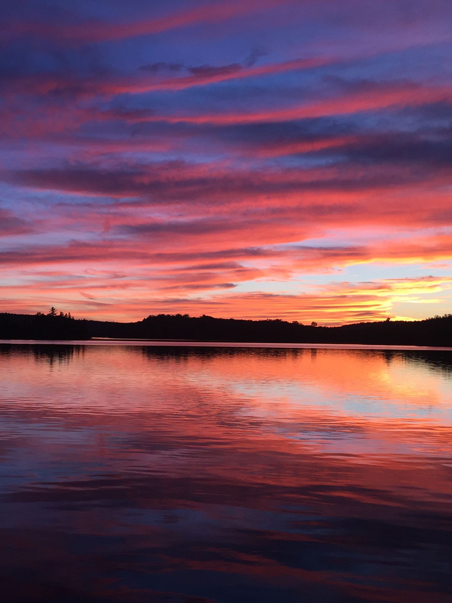 A colorful sunset over a lake with a reflection of the sky in the water.