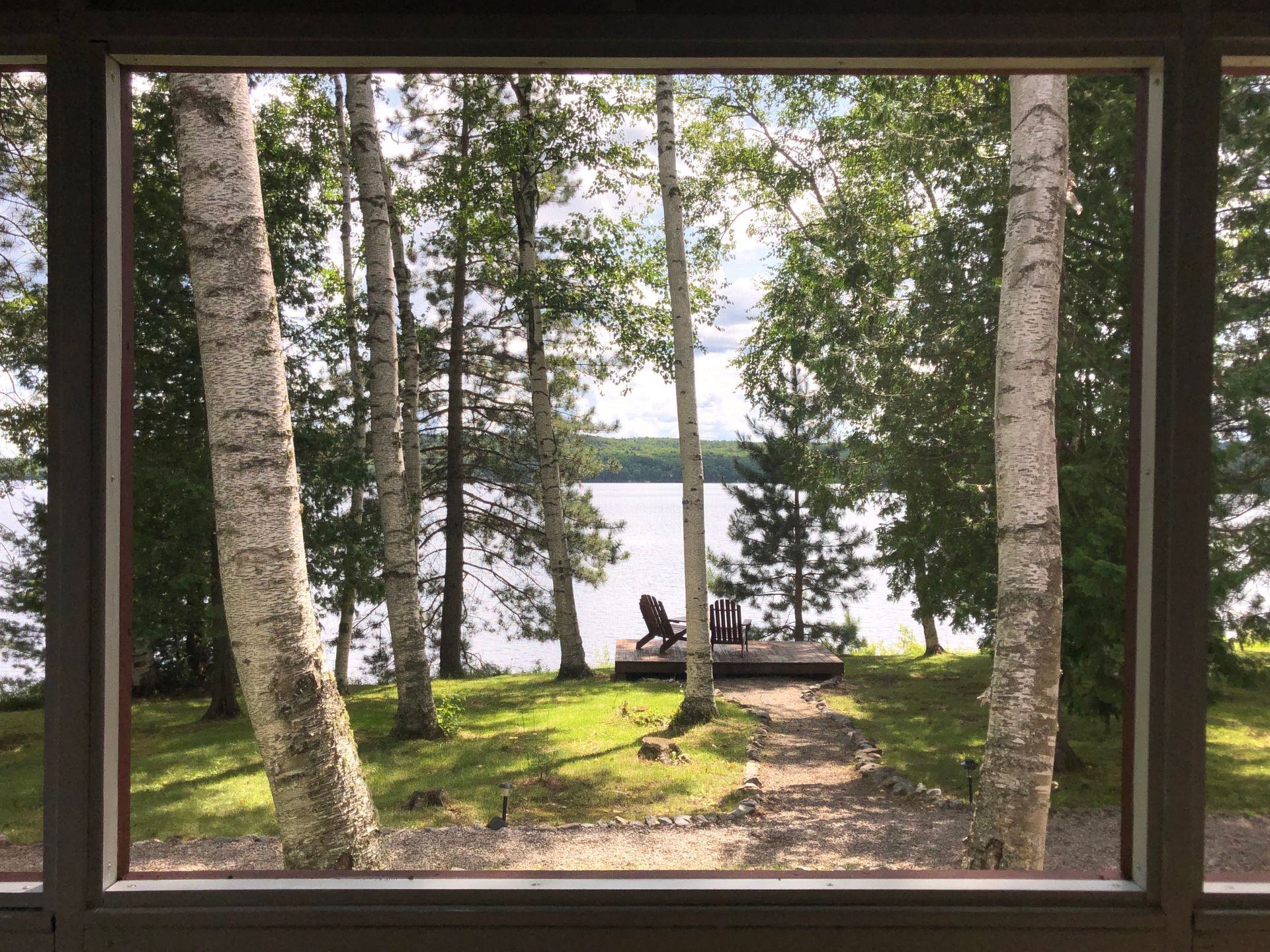 A view of a lake through a window surrounded by trees.