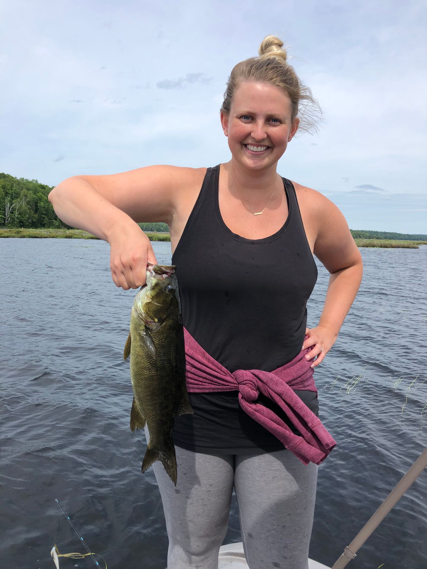 A woman is holding a large fish on a boat