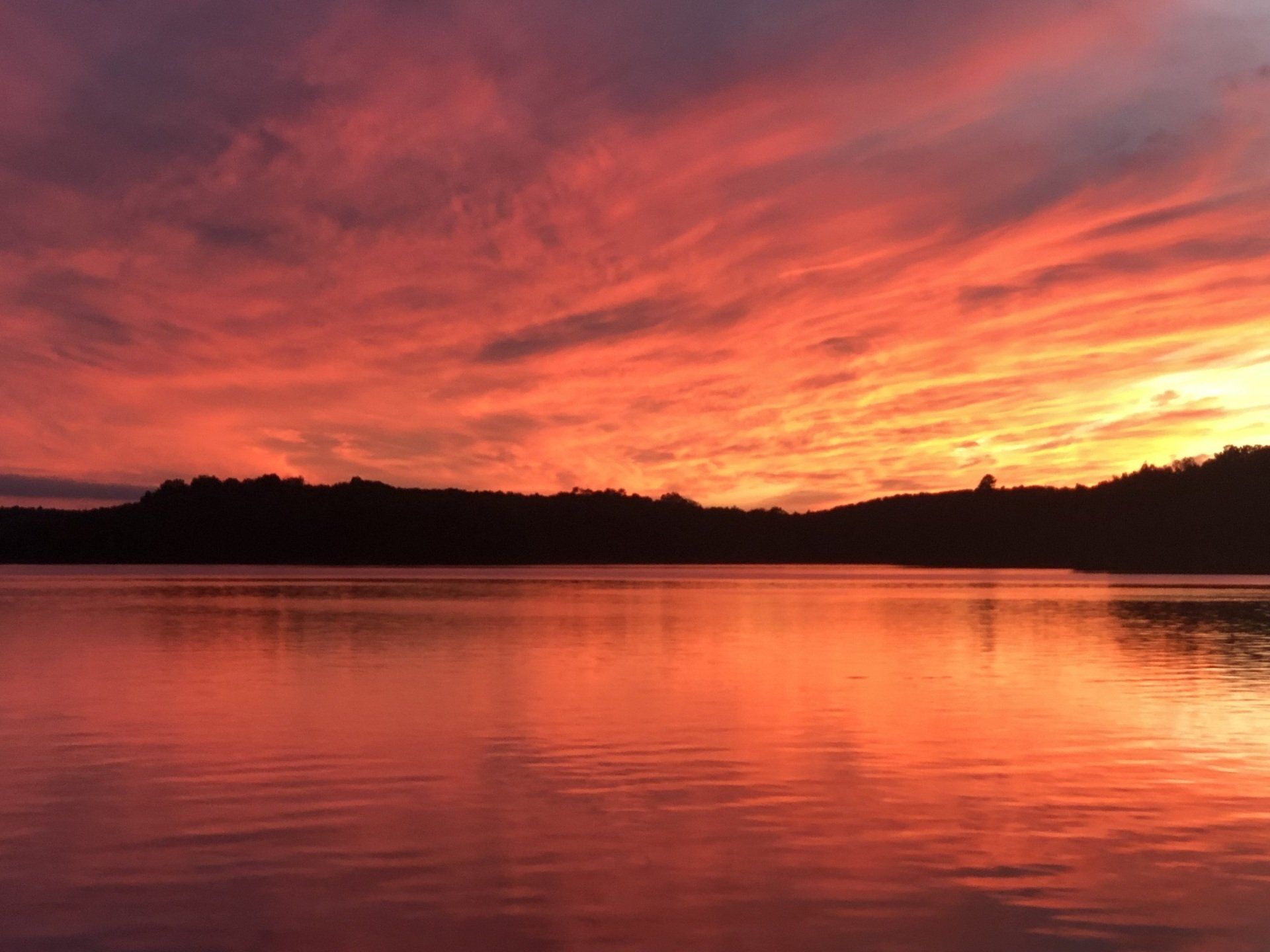 A sunset over a lake with mountains in the background