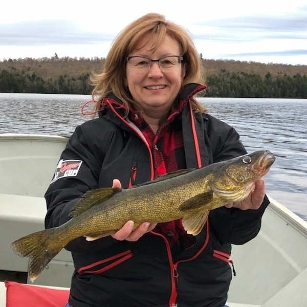 A woman is holding a large fish on a boat
