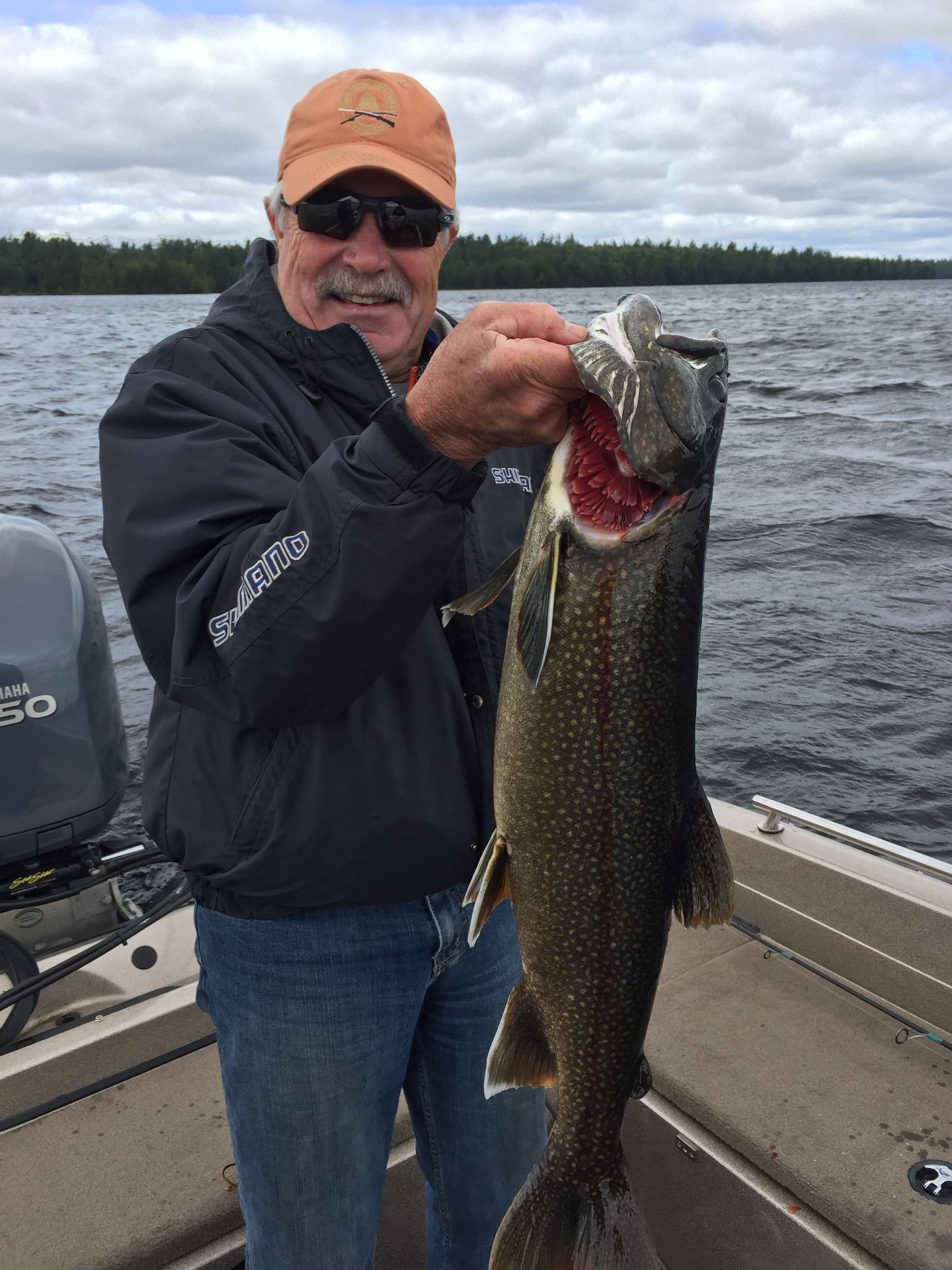 A man is holding a large fish in his hands on a boat.