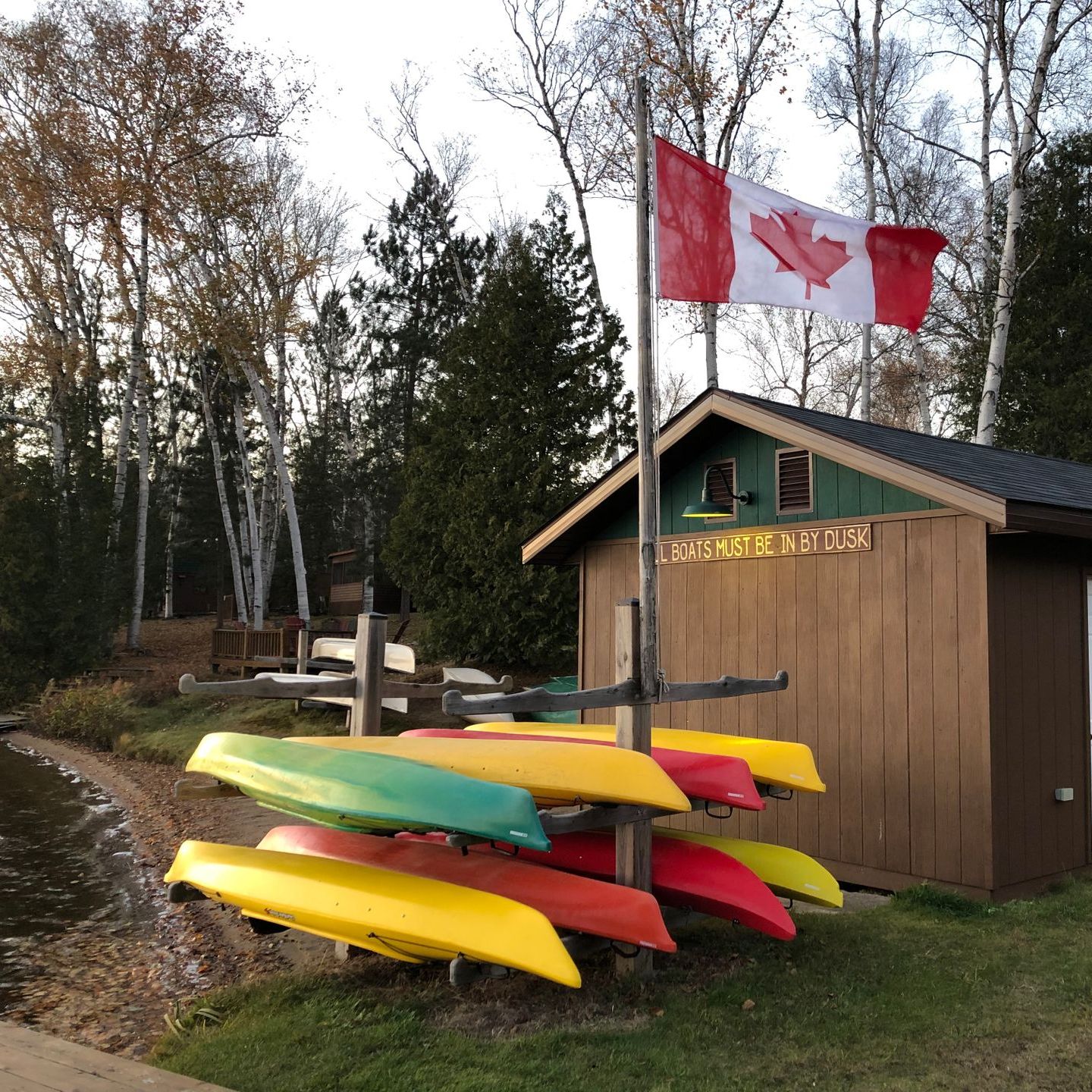 A canadian flag is flying over a row of kayaks