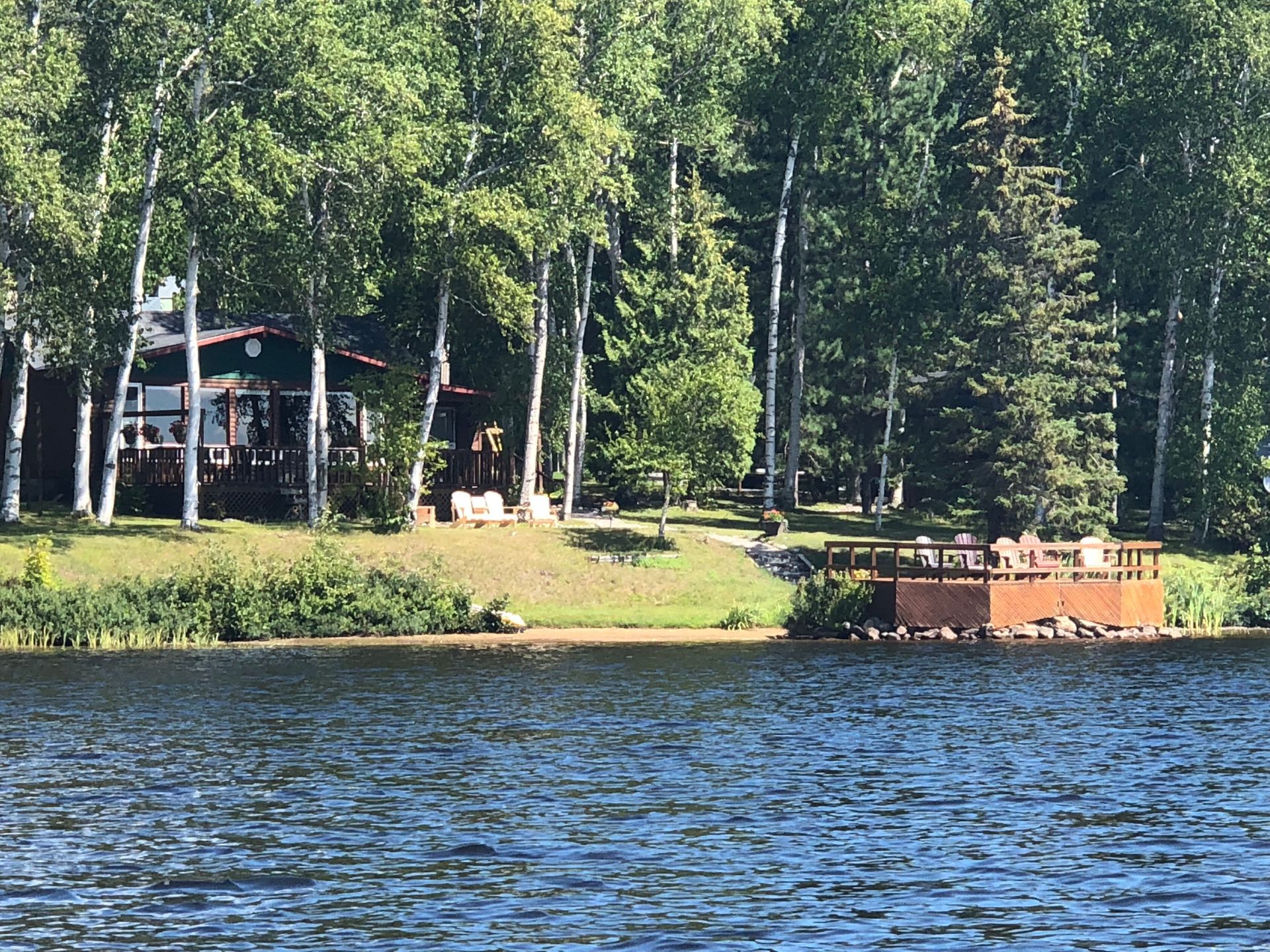A cottage sitting on the shore of a lake surrounded by trees.
