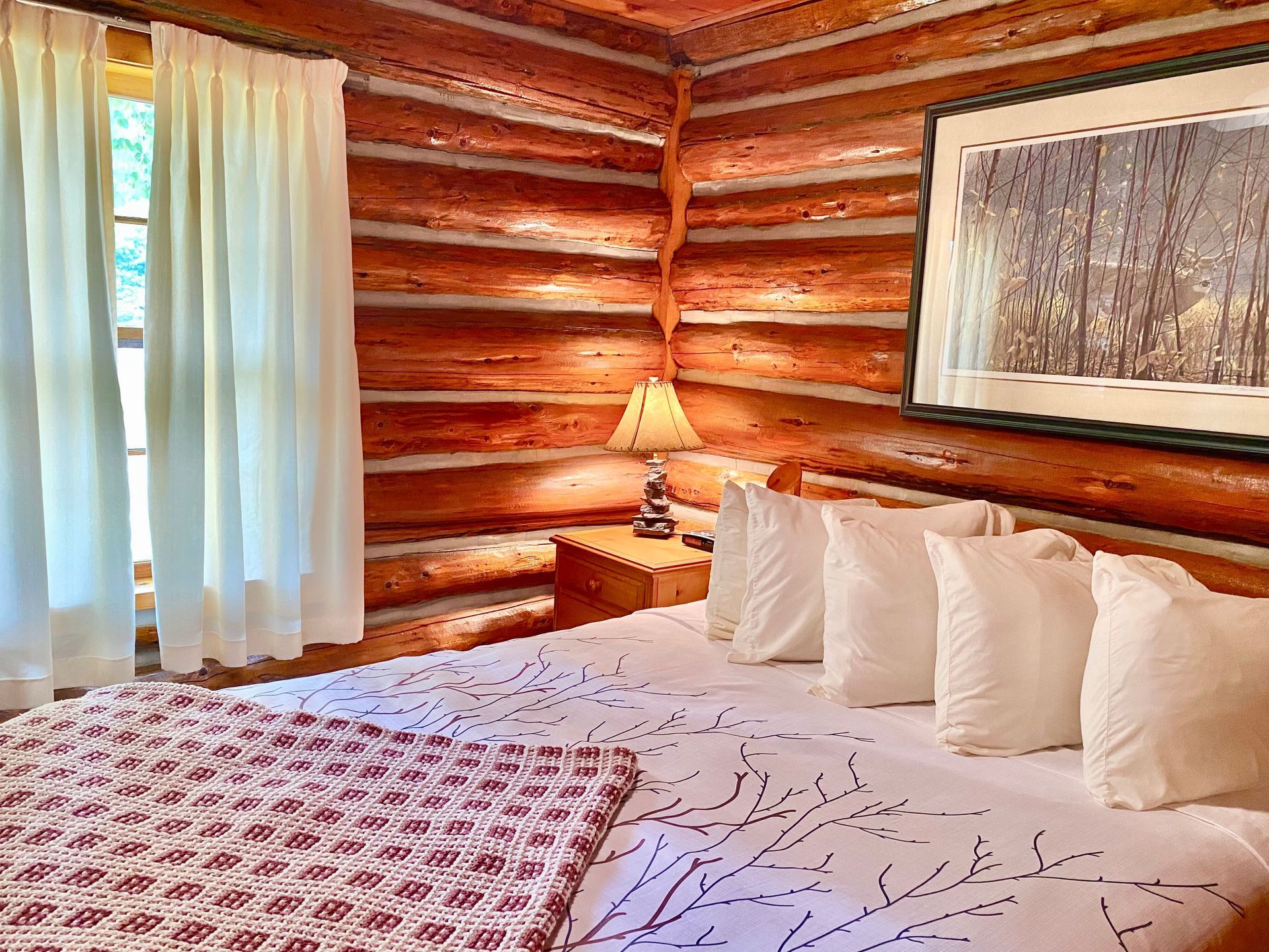 A bedroom in White Pine cottage with a bed and a lamp.