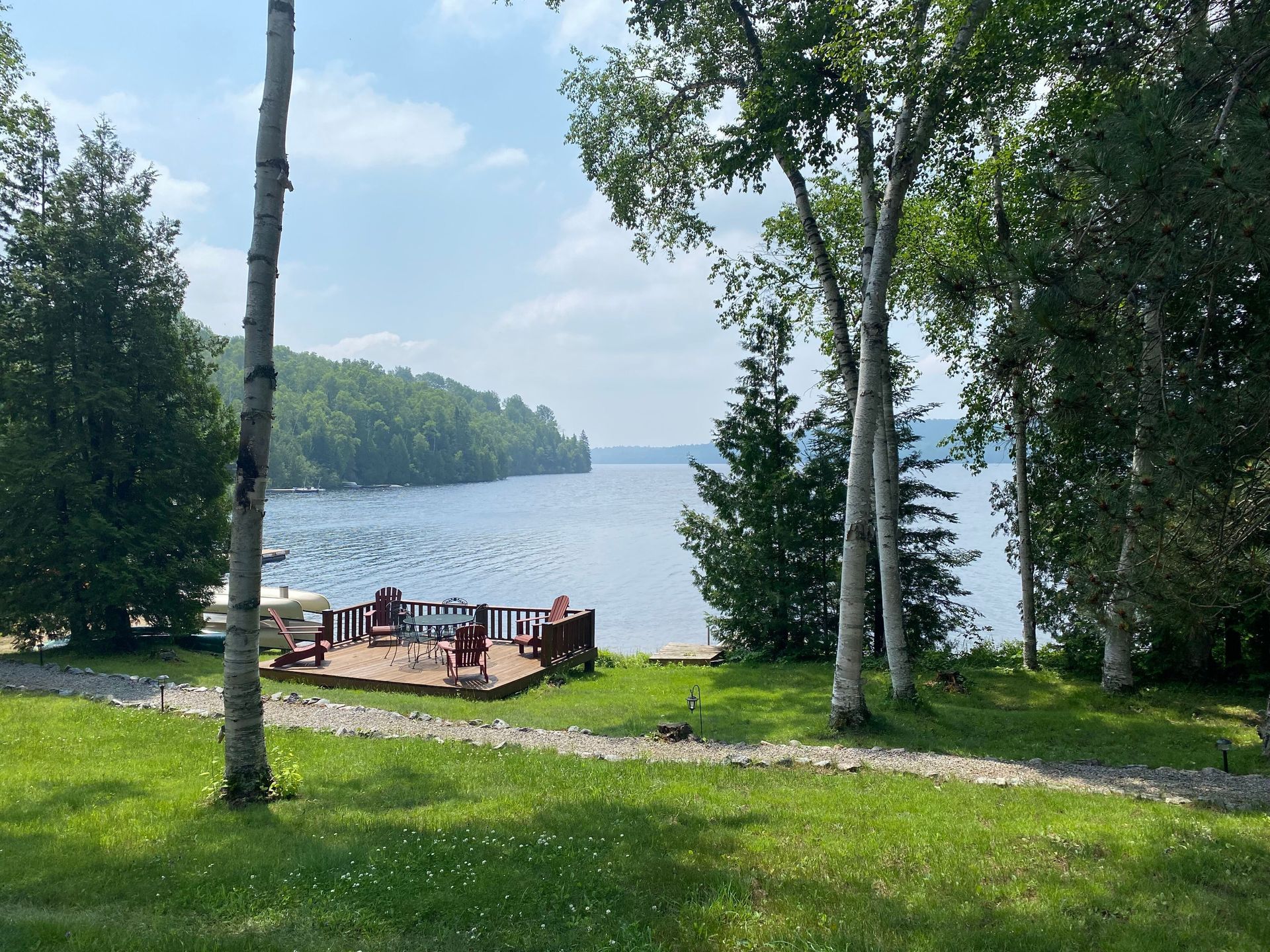 A view of a lake from a grassy area surrounded by trees.