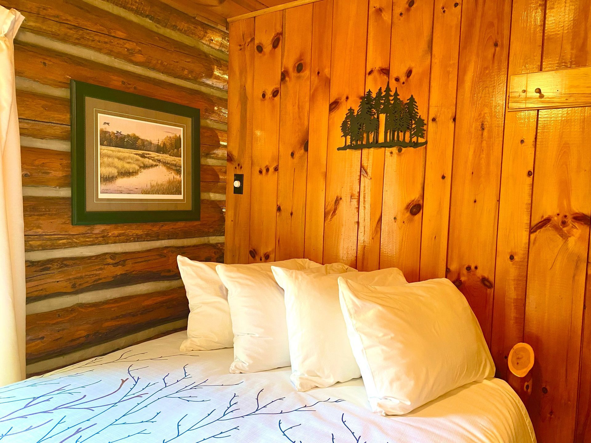 A bedroom in White Pine cottage with a bed and a picture on the wall.