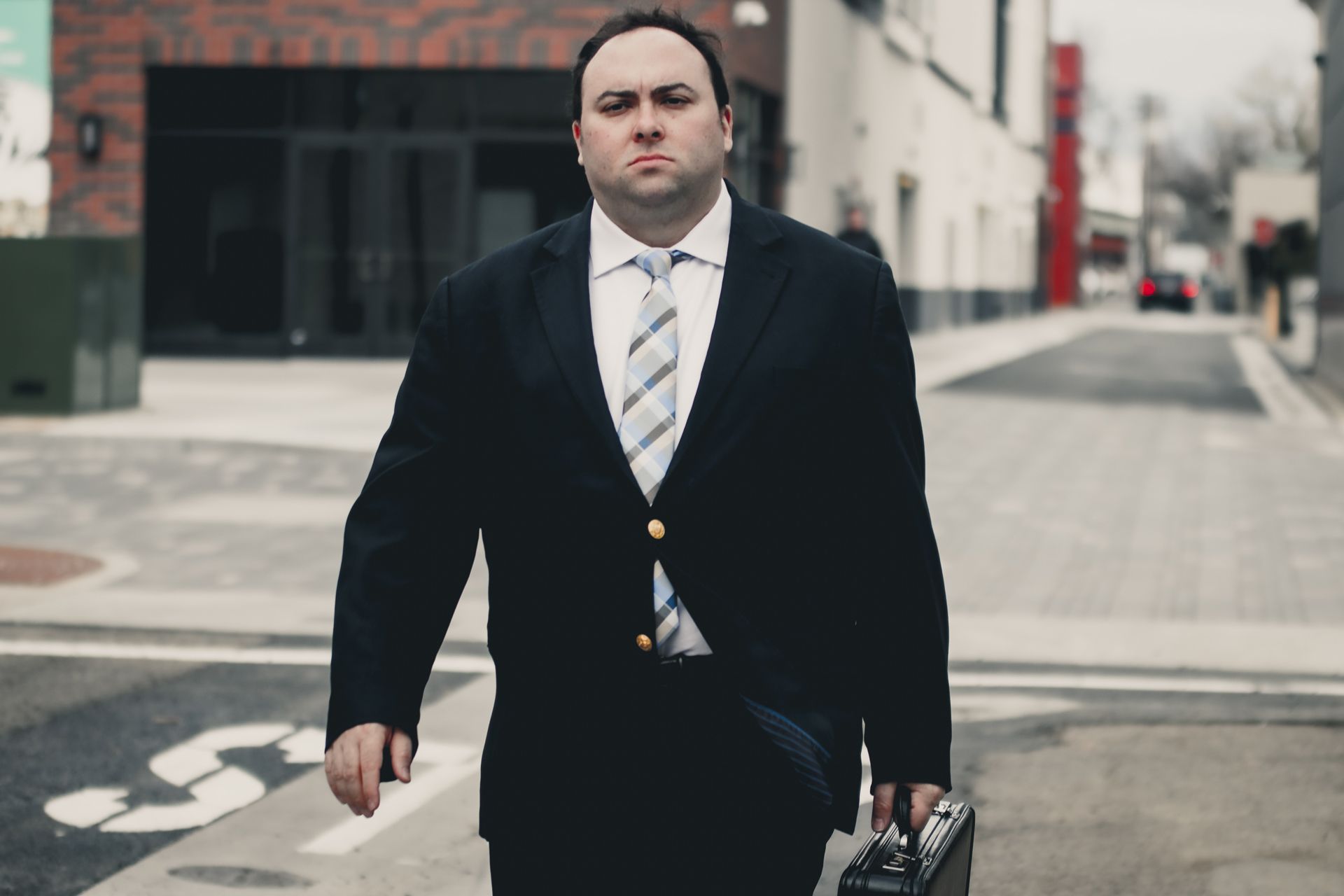 A man in a suit and tie is walking down the street holding a briefcase.