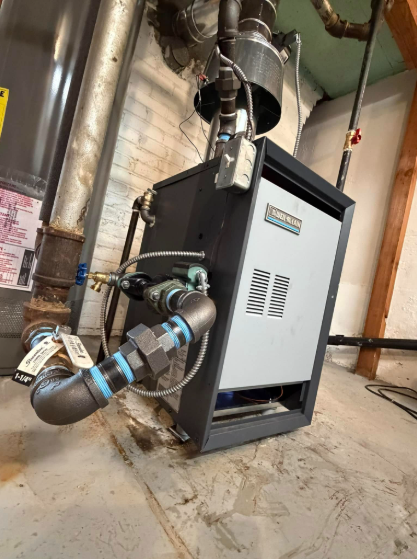 Furnace in basement; gray and black with connected pipes and vent.