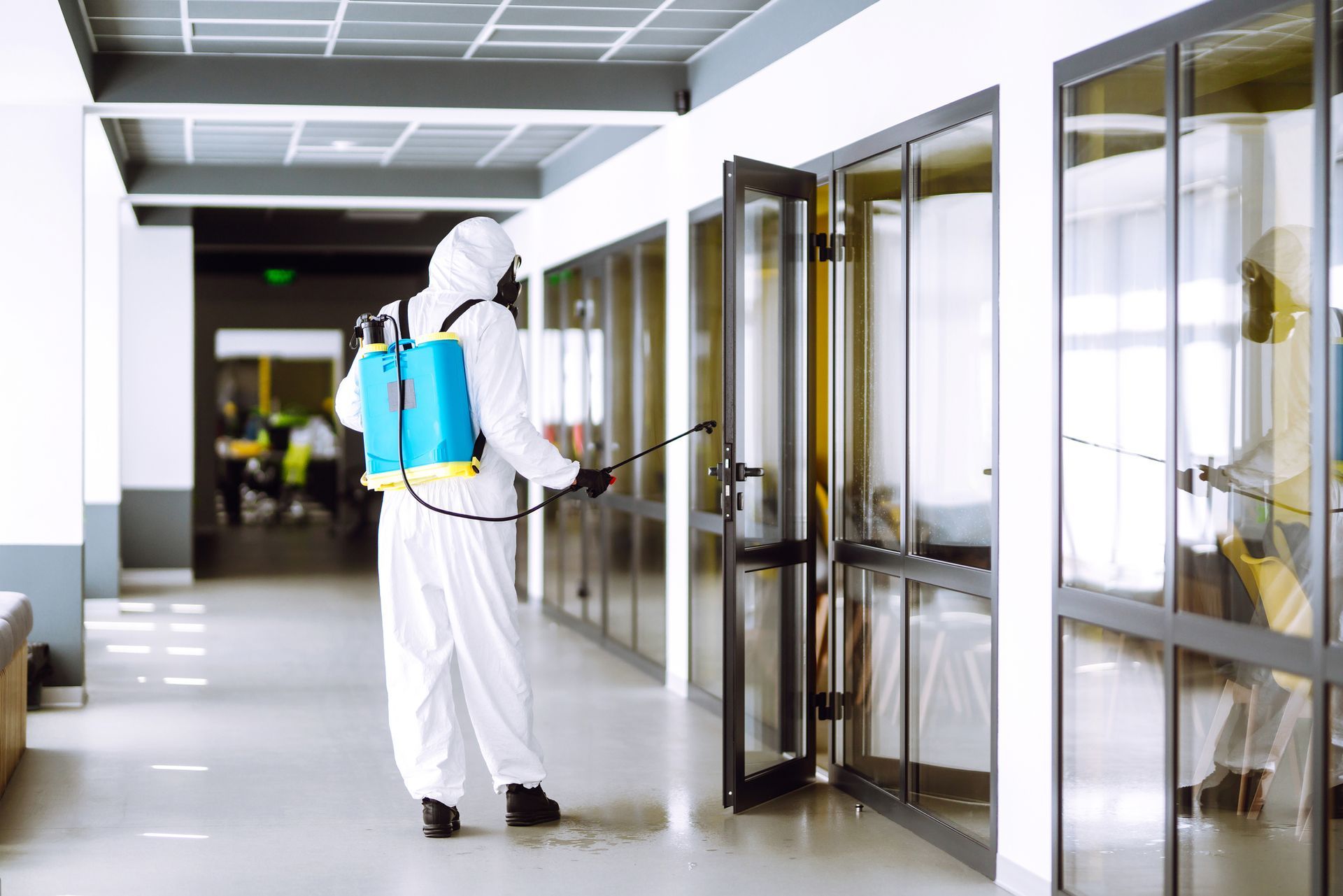 A man in a protective suit is disinfecting a building.