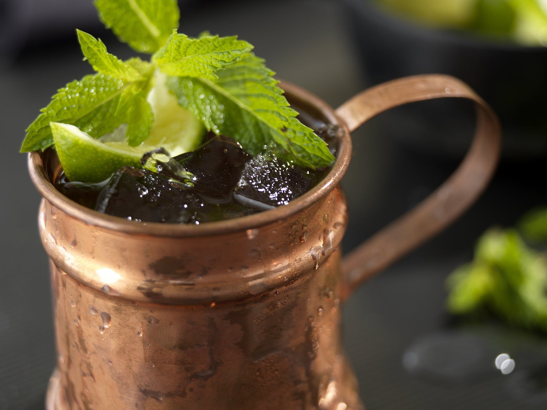 A close up of a copper mug filled with ice and mint leaves.