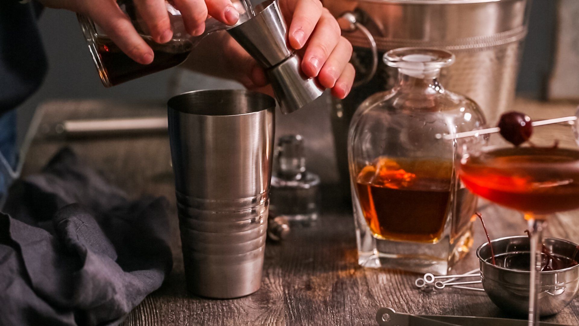 A person is pouring a drink from a shaker into a glass.