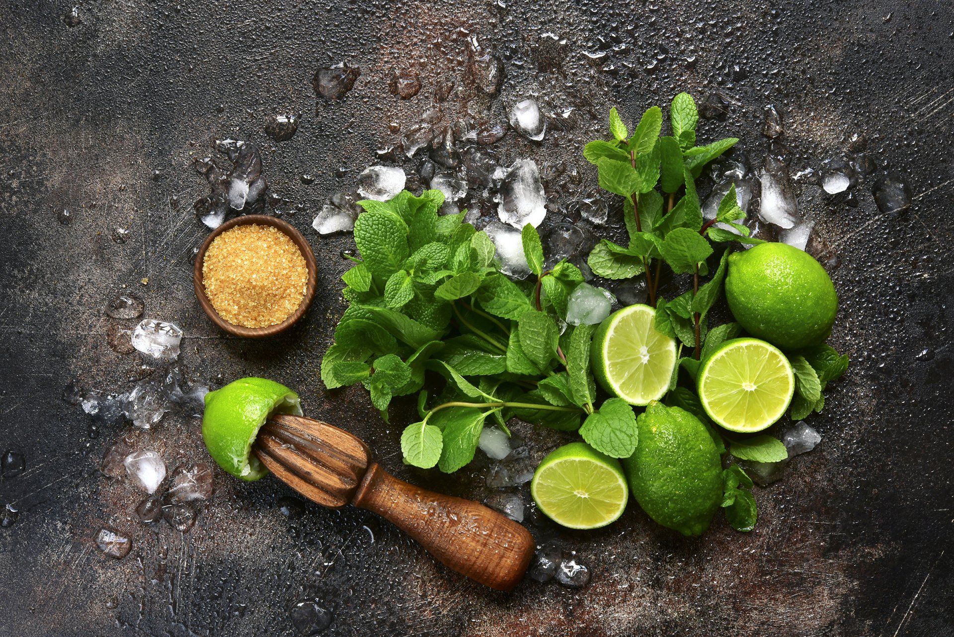 There are limes , mint , ice and sugar on the table.