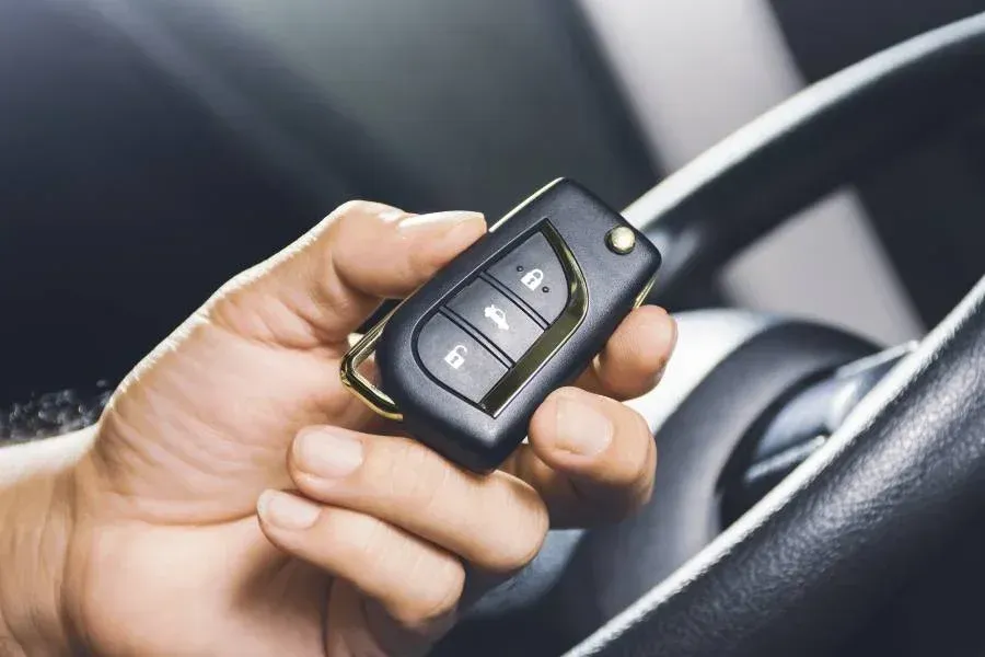 Locksmith attempting to unlock a car door using a lockpicker tool.