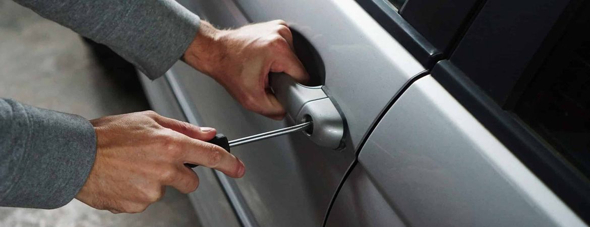 Locksmith attempting to unlock a car door using a lockpicker tool.