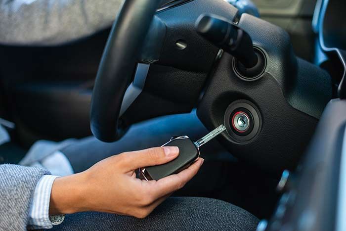 Man using lockpicker to unlock a red car door.