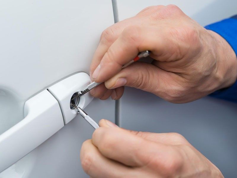 Man using lockpicker to unlock a red car door.