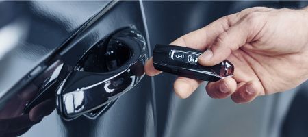 Man using lockpicker to unlock a red car door.