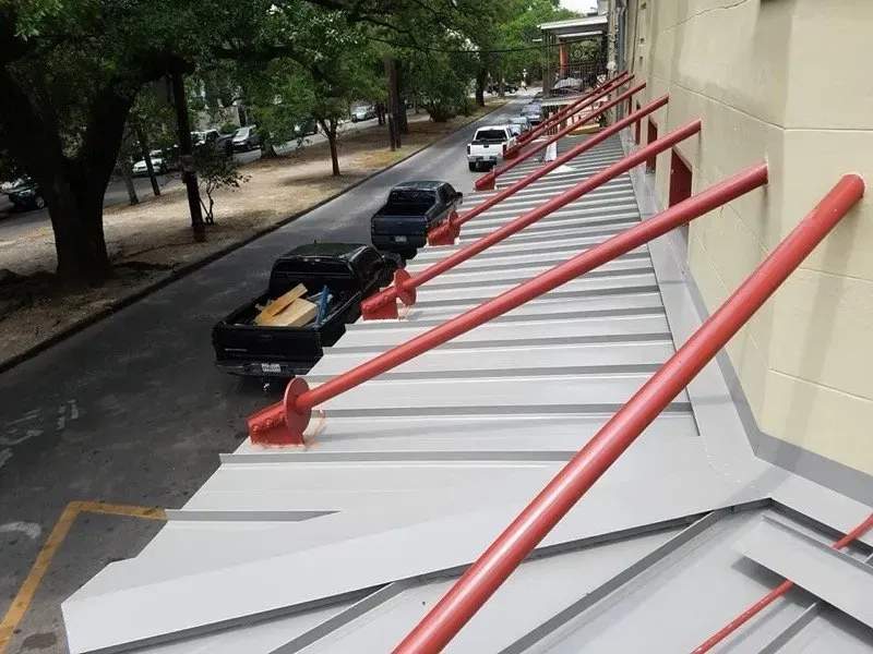 Angled red support beams extending from a building roof. Black trucks parked along the street.